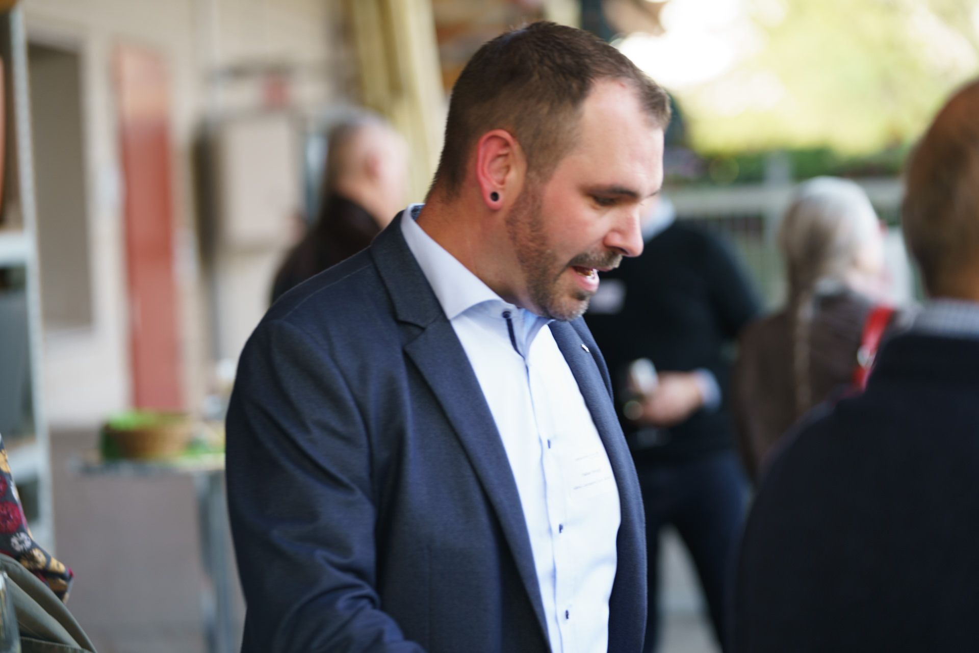 Ein Mann in Anzug und weißem Hemd spricht mit einer Gruppe von Leuten.