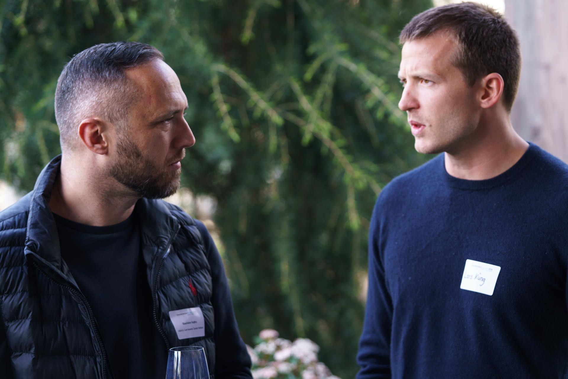 Zwei Männer stehen nebeneinander und unterhalten sich.