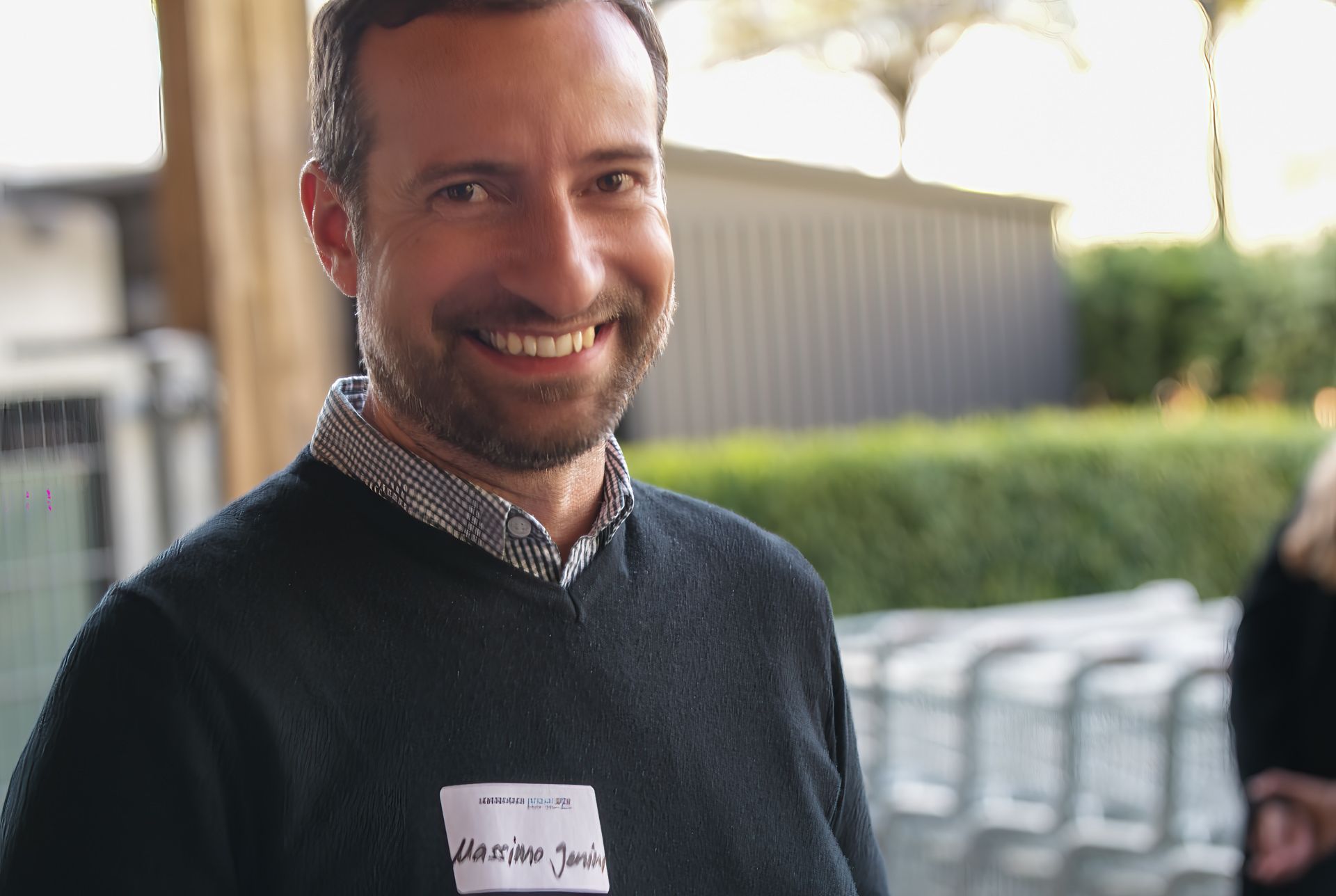 Ein Mann mit einem Namensschild auf seinem Pullover lächelt