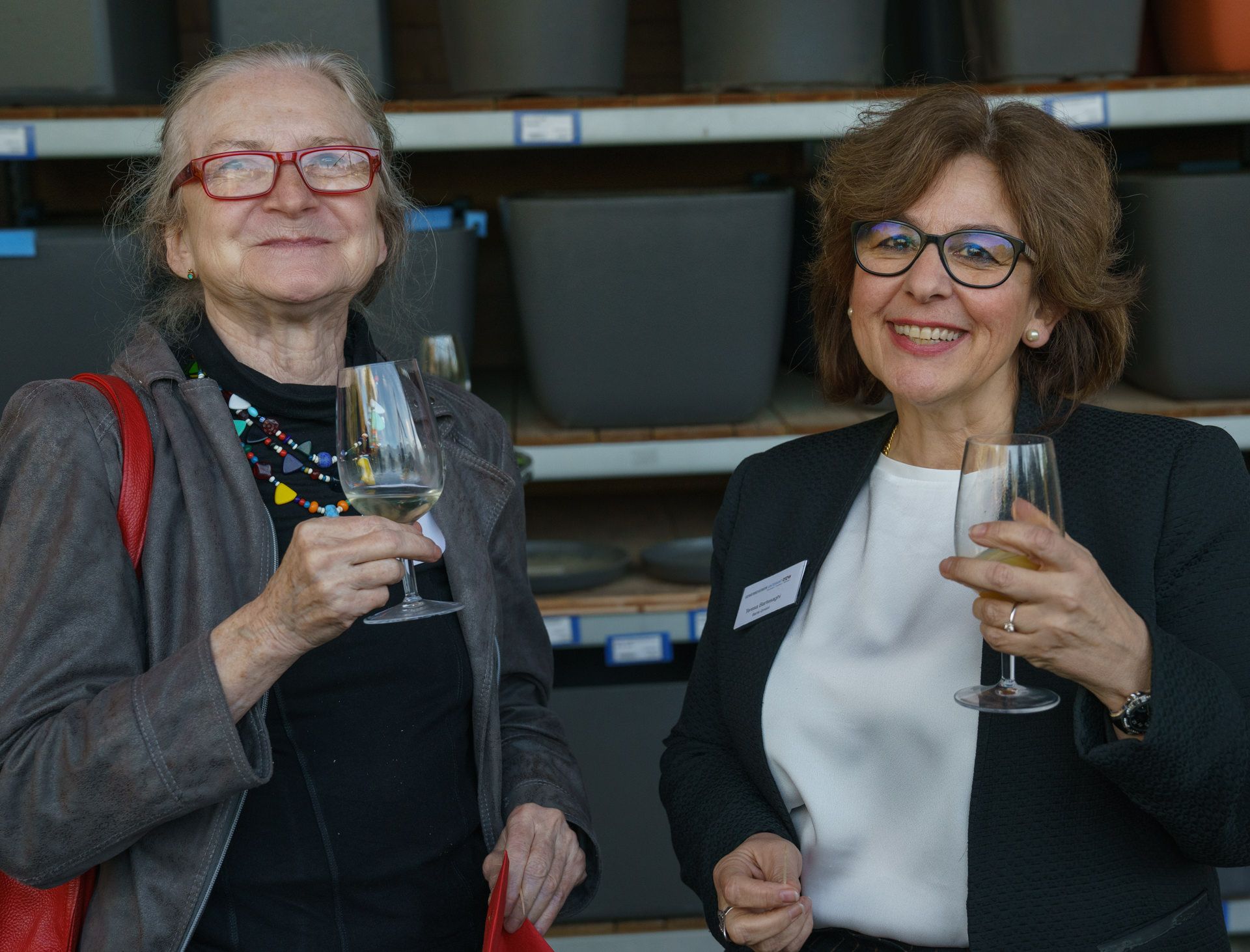 Zwei Frauen stehen nebeneinander und halten Weingläser.