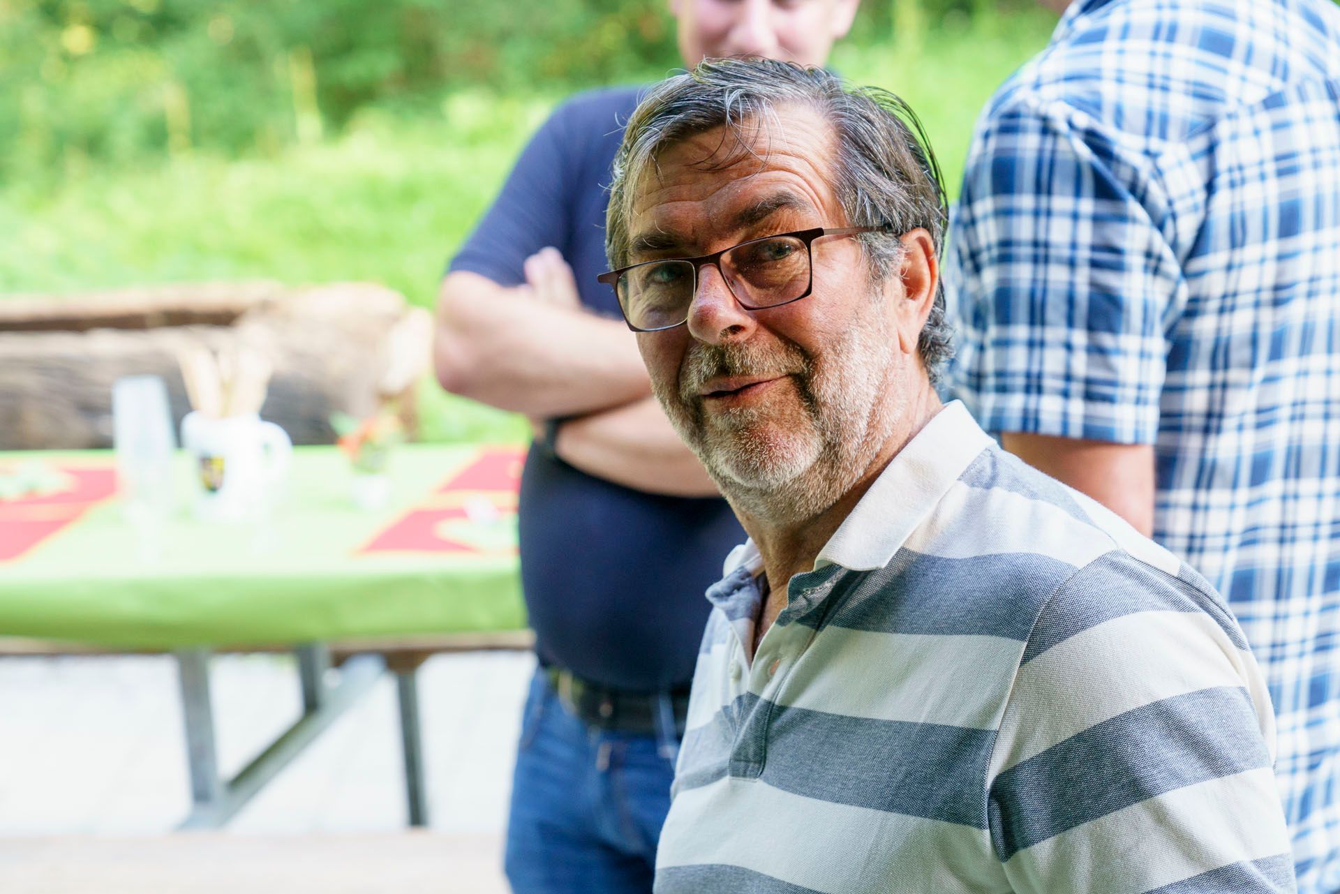 Ein Mann mit Brille und gestreiftem Hemd steht vor einem Tisch.