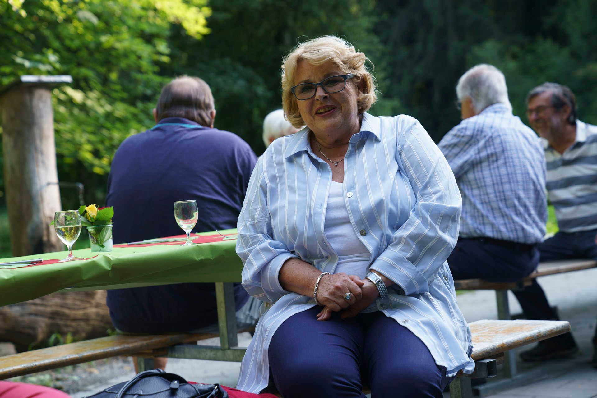 Eine Frau sitzt auf einer Bank an einem Picknicktisch.
