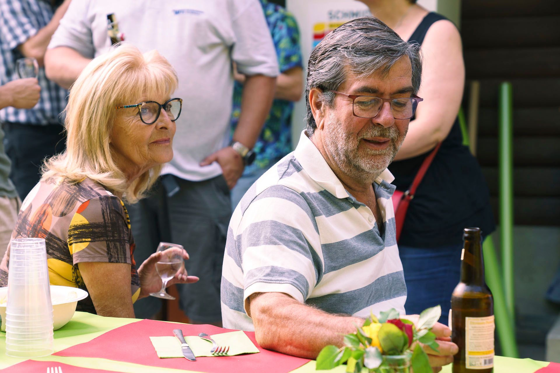 Ein Mann und eine Frau sitzen mit einer Flasche Bier an einem Tisch.