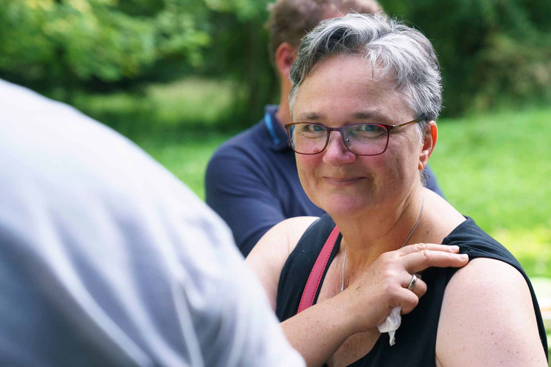 Eine Frau mit Brille und schwarzem Tanktop spricht mit einem Mann.