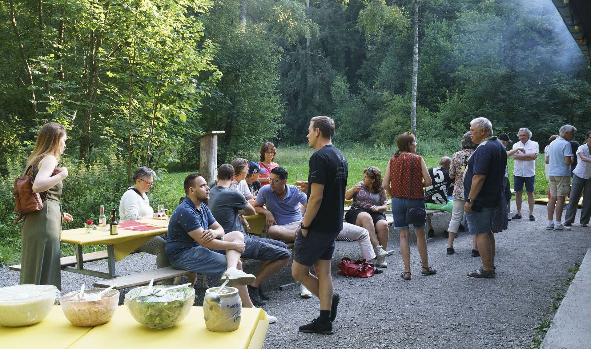 Eine Gruppe von Leuten sitzt an einem Picknicktisch im Wald.