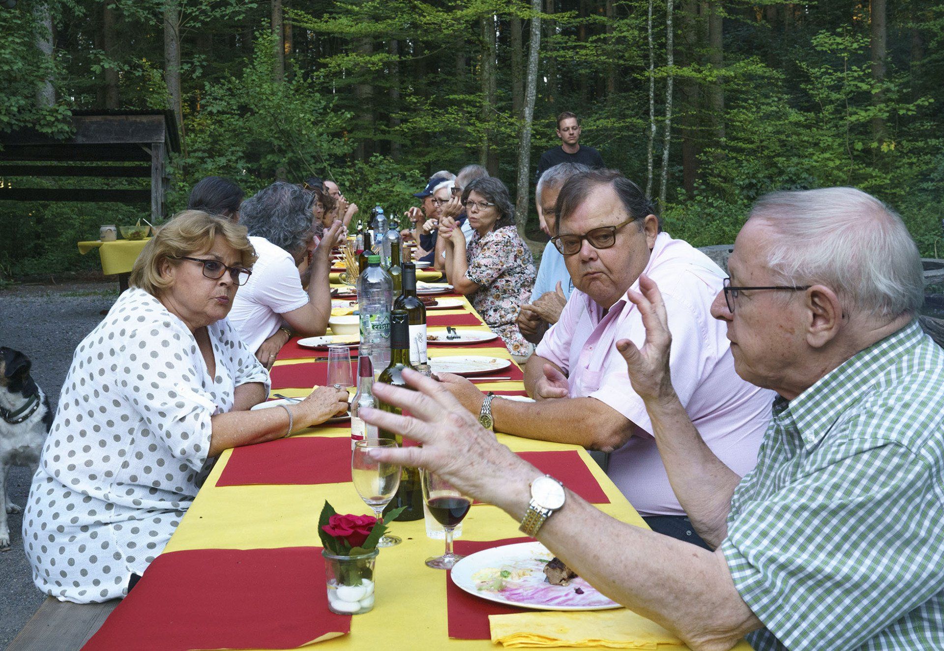 Eine Gruppe von Leuten sitzt an einem langen Tisch und isst und trinkt.