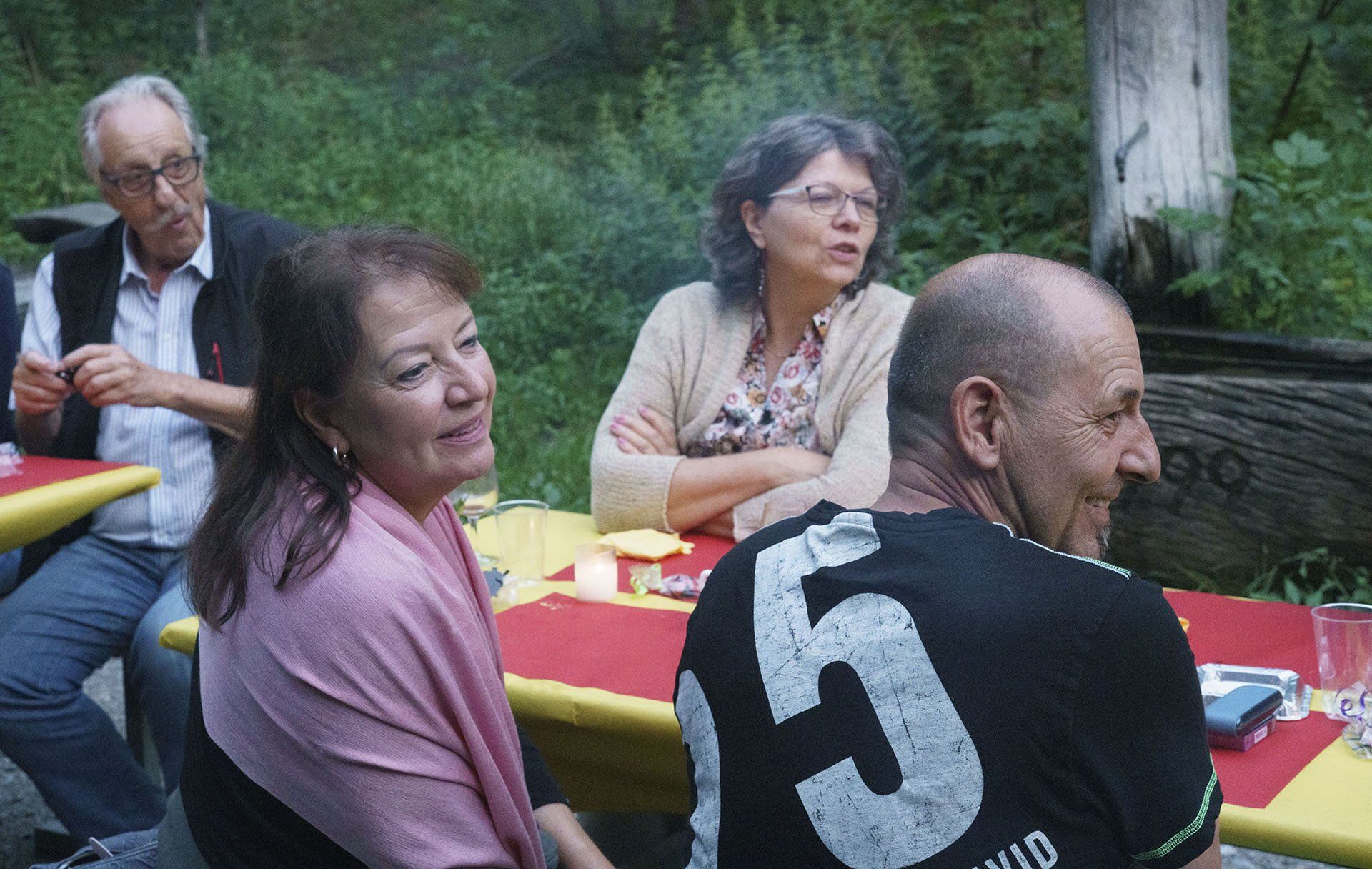 Eine Gruppe von Leuten sitzt an einem Tisch im Wald.