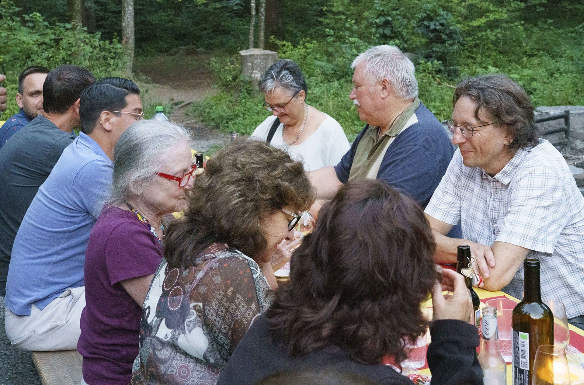 Eine Gruppe von Leuten sitzt mit Weinflaschen an einem Tisch.
