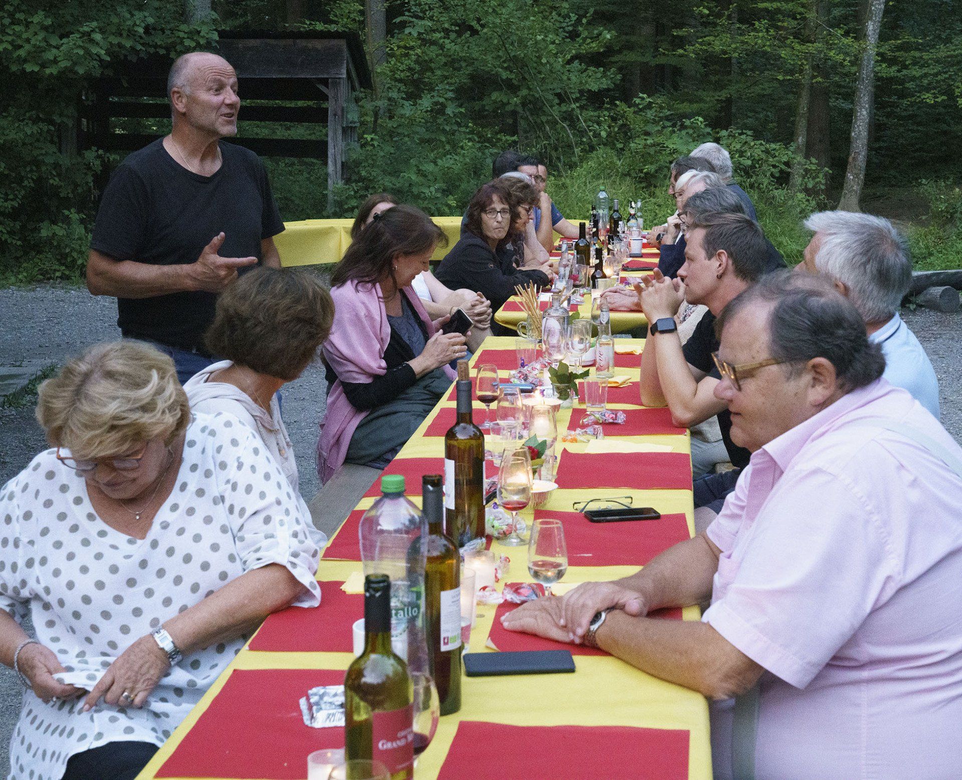 Eine Gruppe von Menschen sitzt an einem langen Tisch mit Weinflaschen