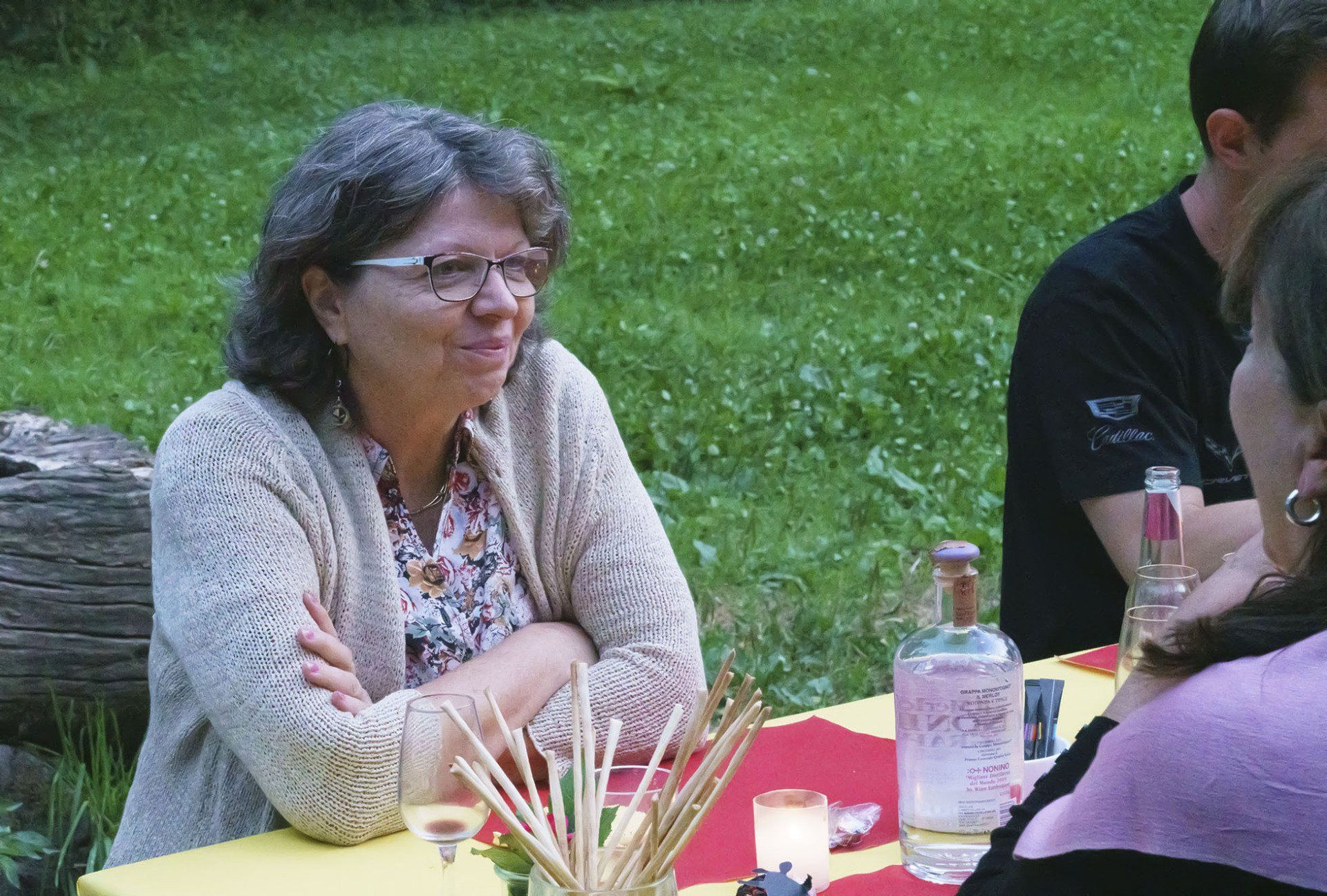 Eine Frau mit Brille sitzt mit anderen Leuten an einem Tisch
