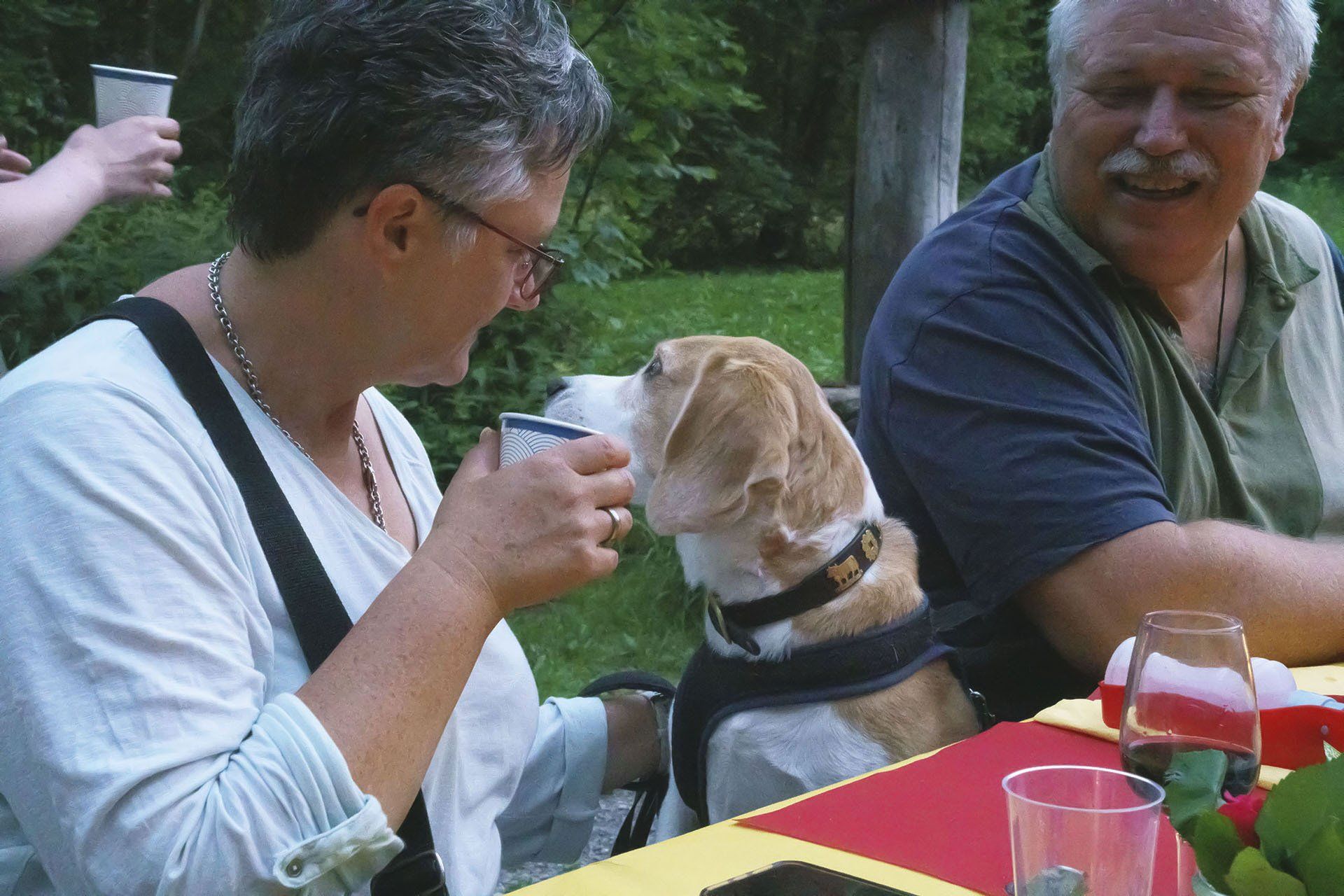 Ein Mann und eine Frau sitzen mit einem Hund an einem Tisch