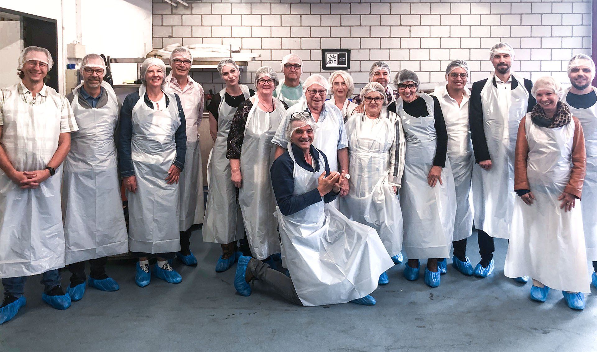 Eine Gruppe von Menschen mit Schürzen und blauen Schuhen posiert für ein Foto.