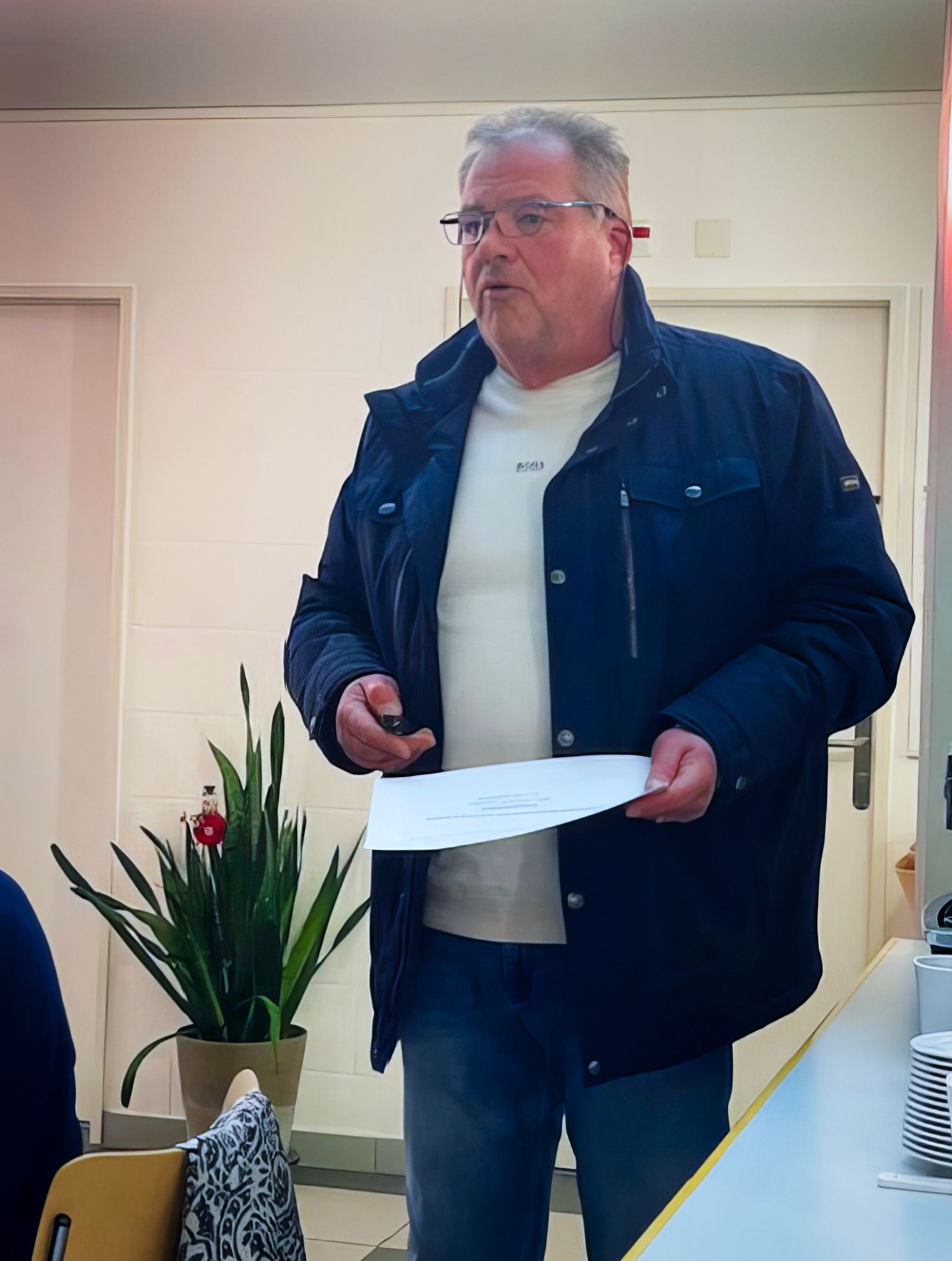 Ein Mann in einer blauen Jacke hält ein Stück Papier