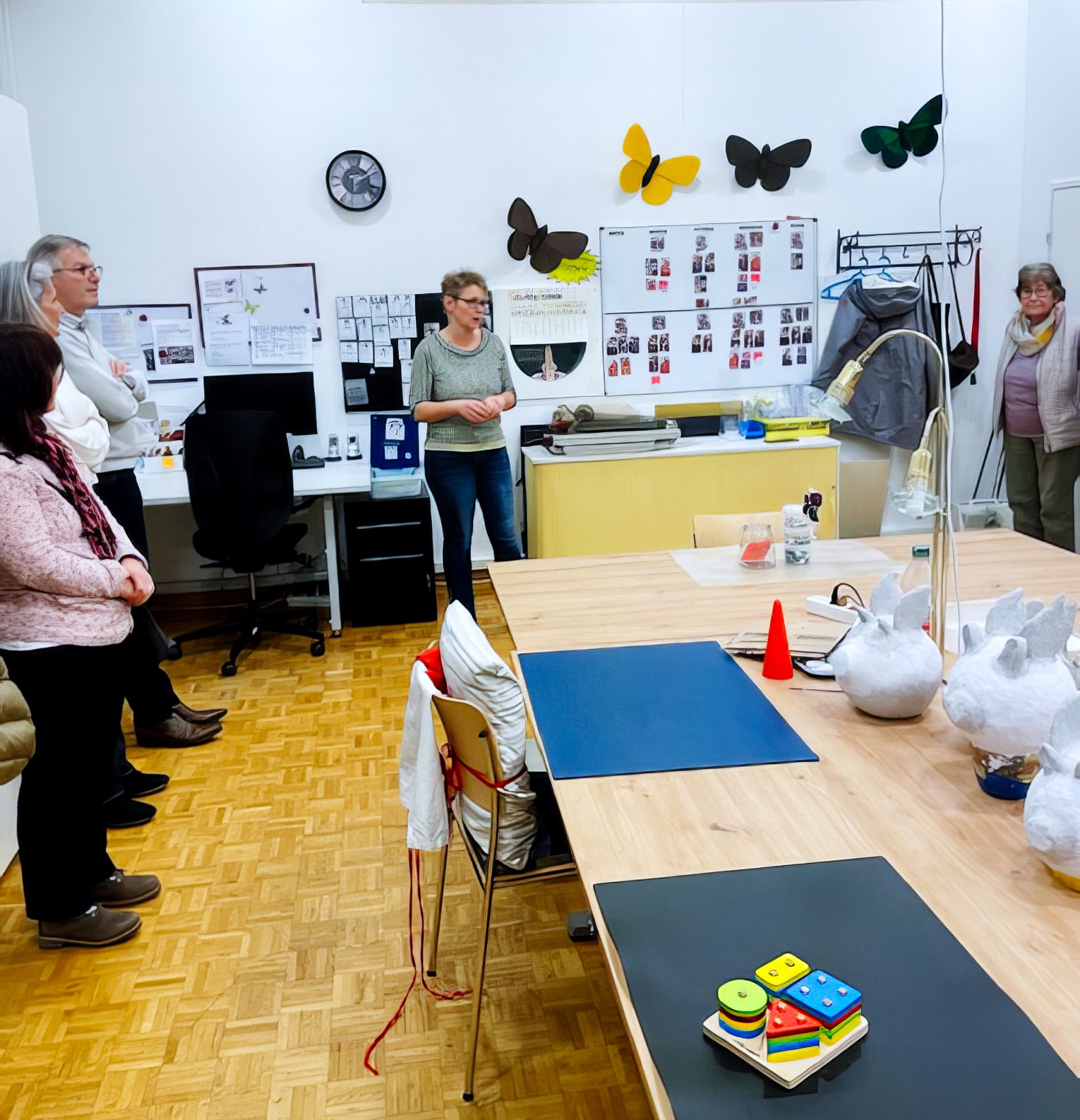 Eine Gruppe von Menschen steht um einen Tisch in einem Raum mit Schmetterlingen an der Wand