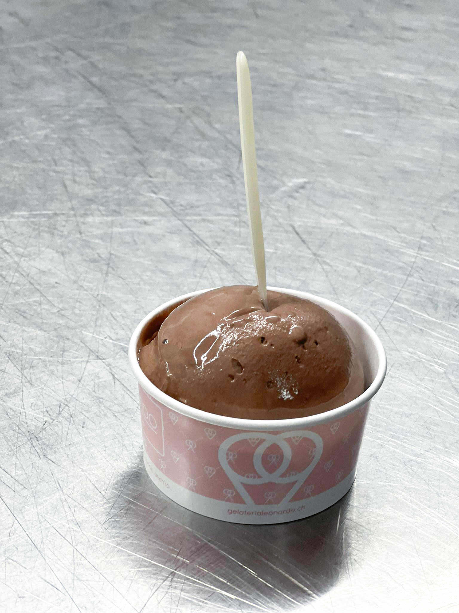 Ein Becher Schokoladeneis, aus dem ein Zahnstocher herausragt.