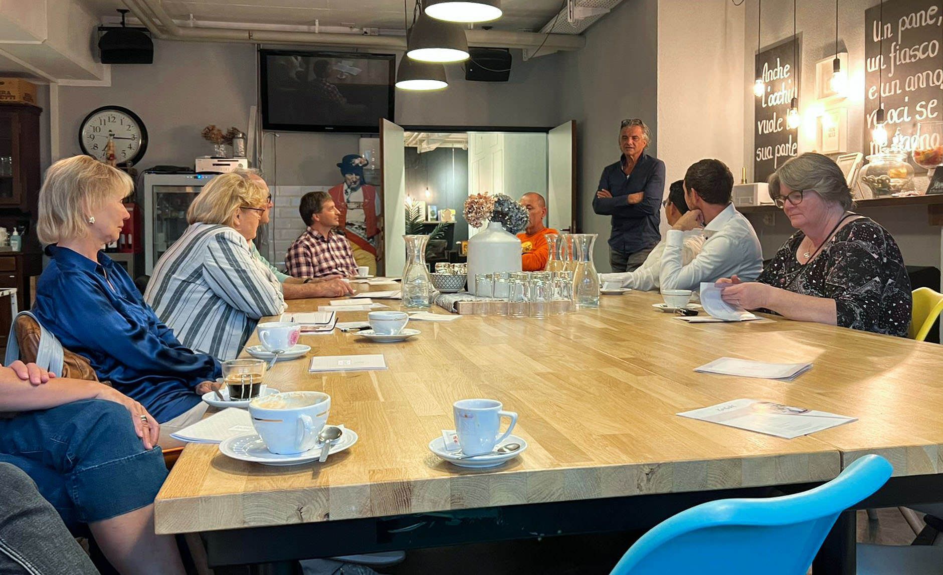 Eine Gruppe von Leuten sitzt um einen langen Holztisch.