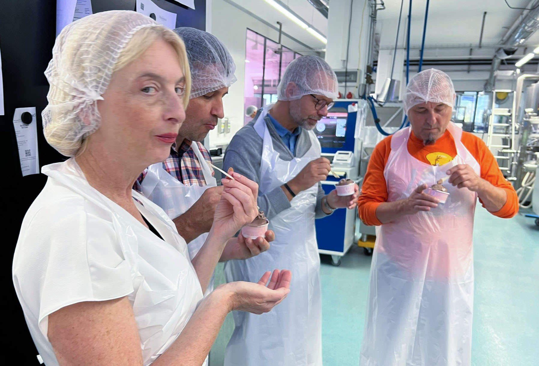 Eine Gruppe Leute isst in einer Fabrik Eis.