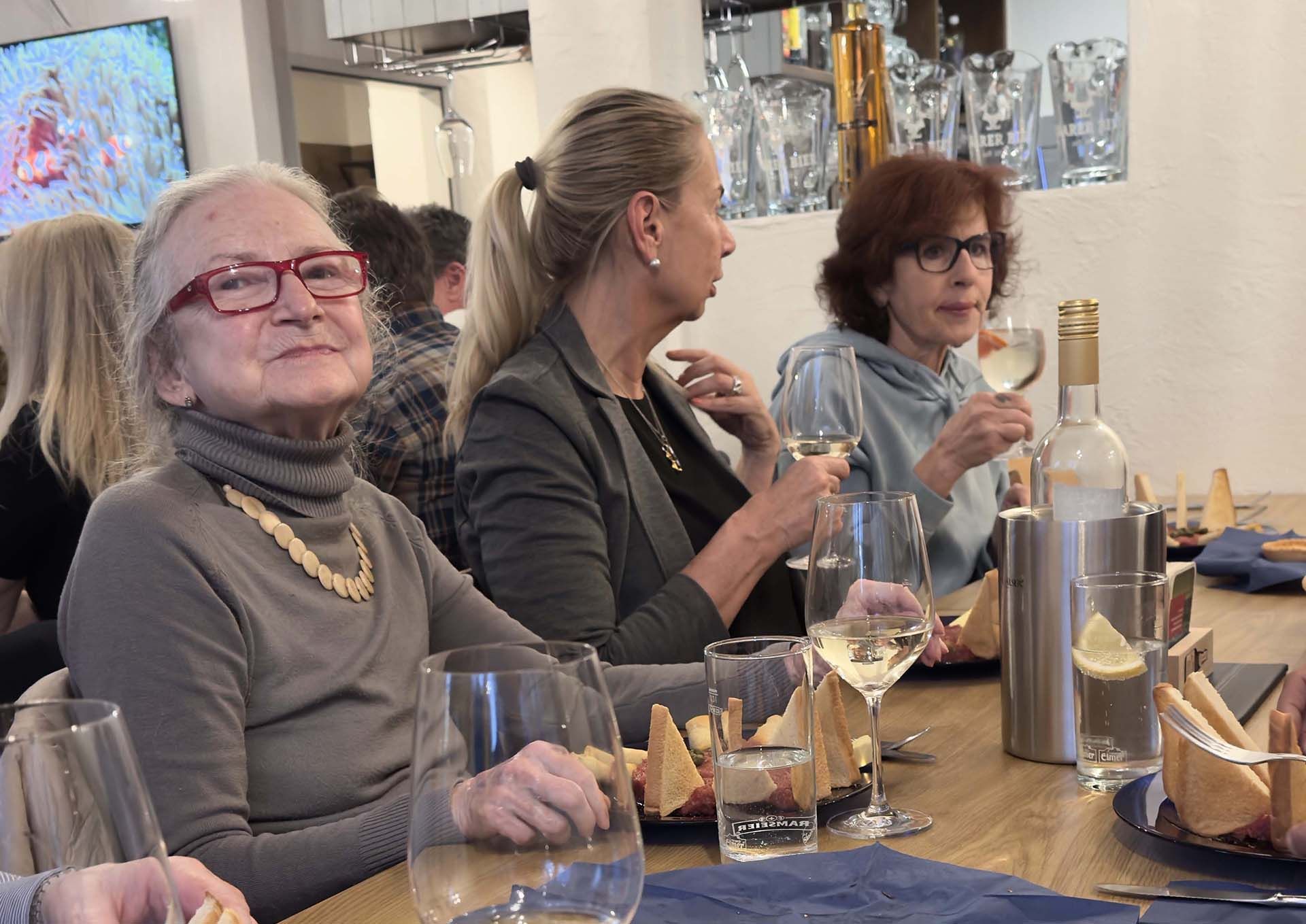 Eine Gruppe Frauen sitzt an einem Tisch und trinkt Wein.