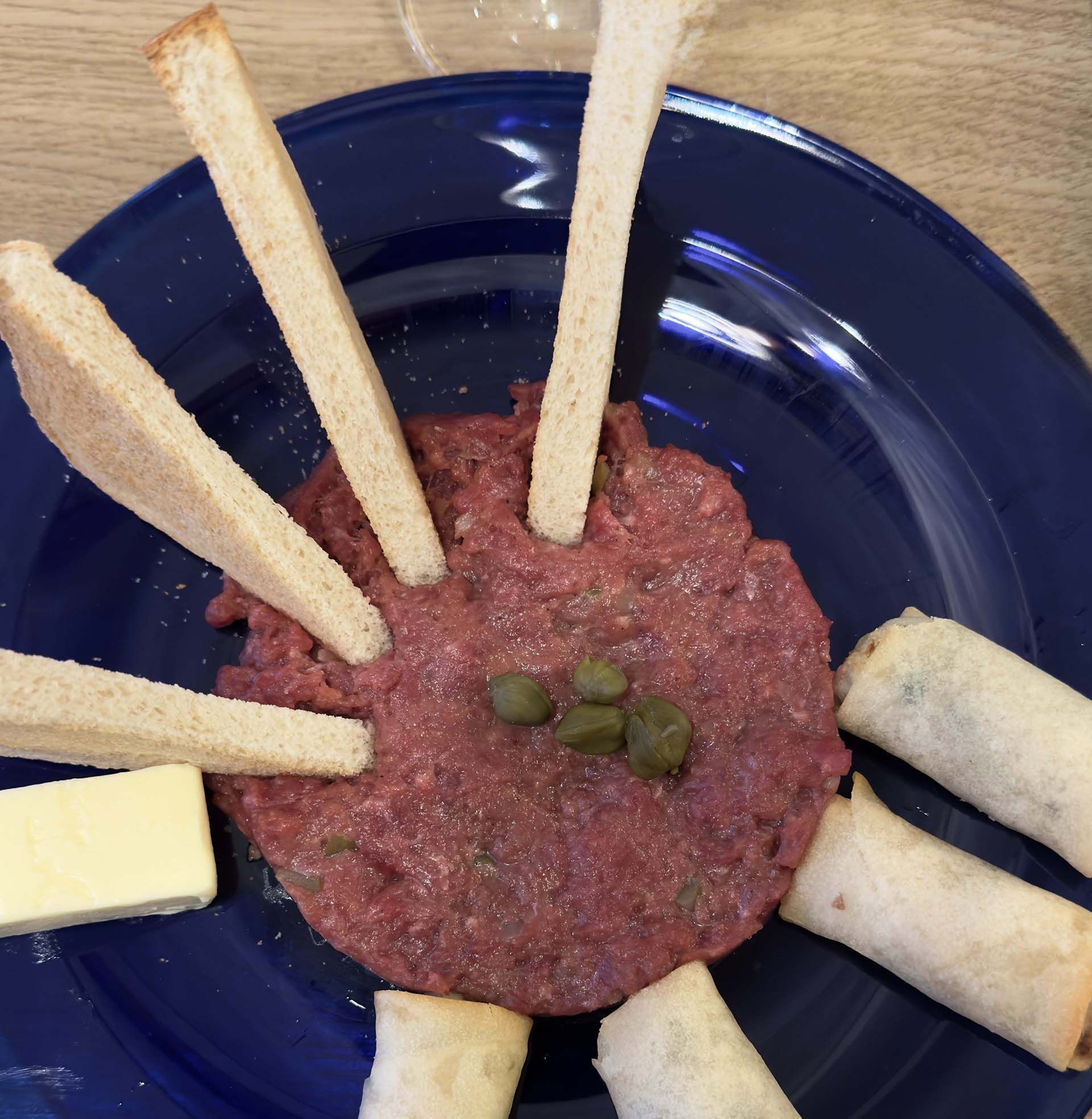 Ein blauer Teller mit Fleisch und Brotstangen