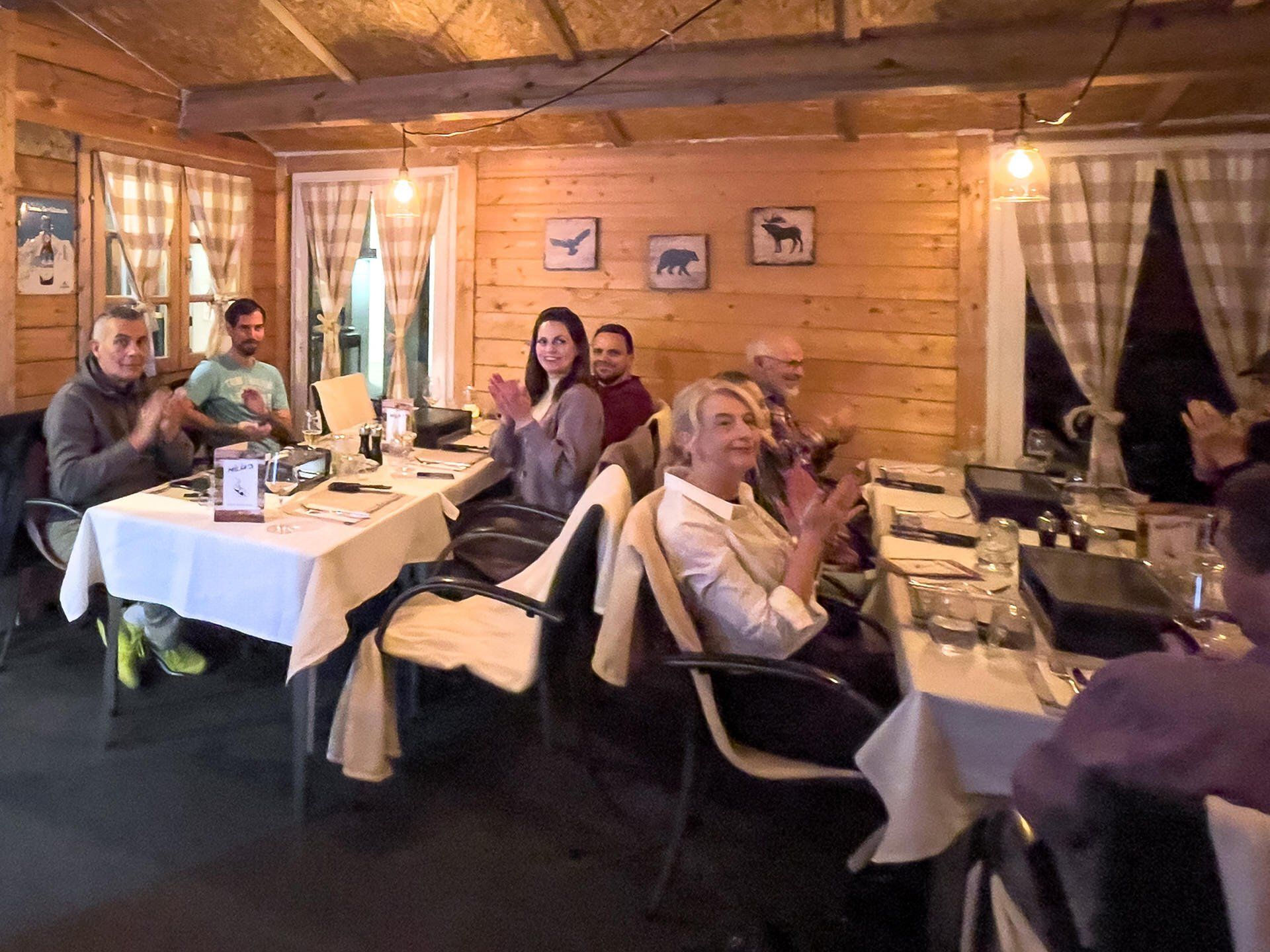 Eine Gruppe von Menschen sitzt an Tischen in einem Restaurant und applaudiert.