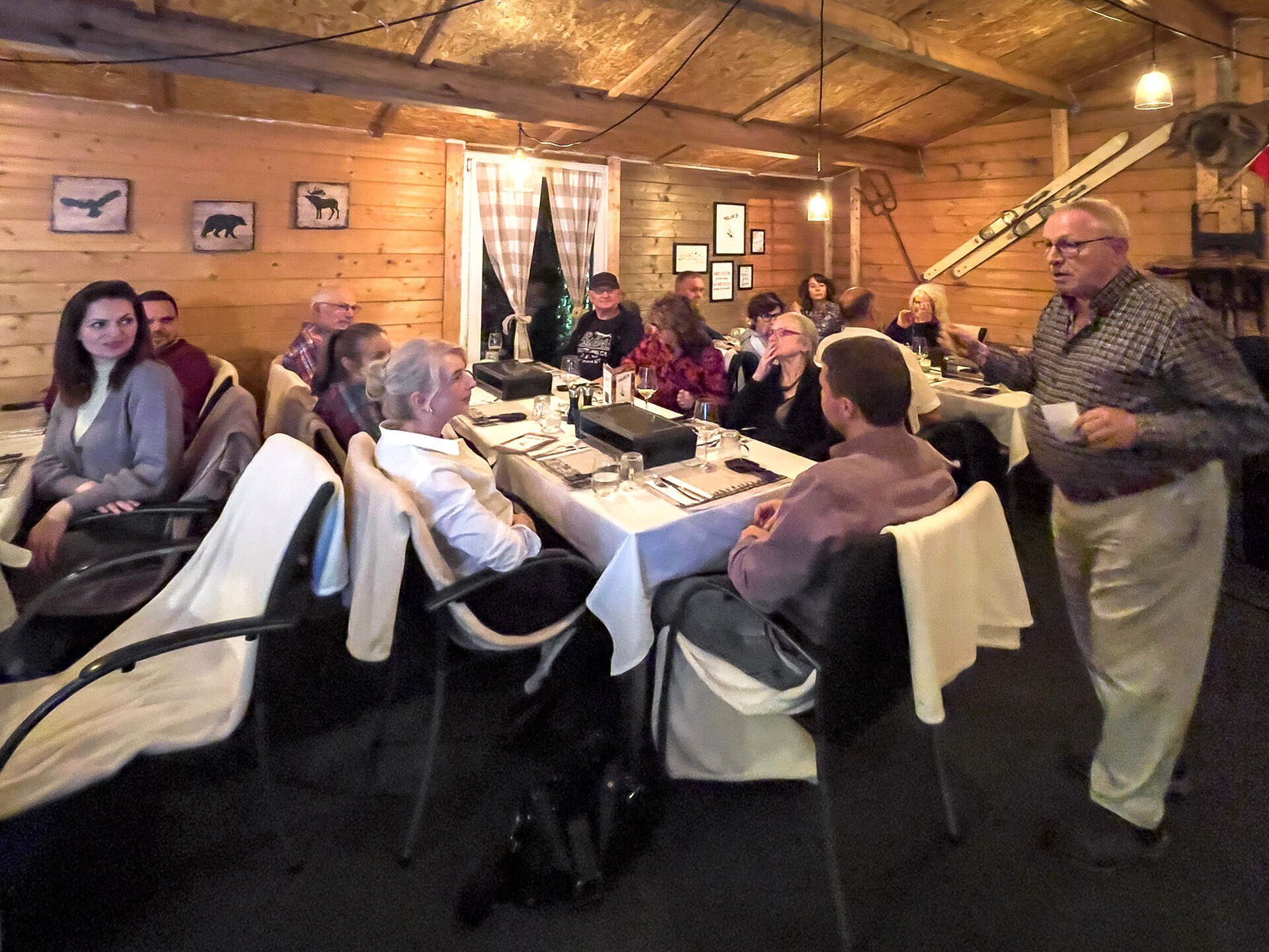 Ein Mann steht vor einer Gruppe von Menschen, die an Tischen sitzen