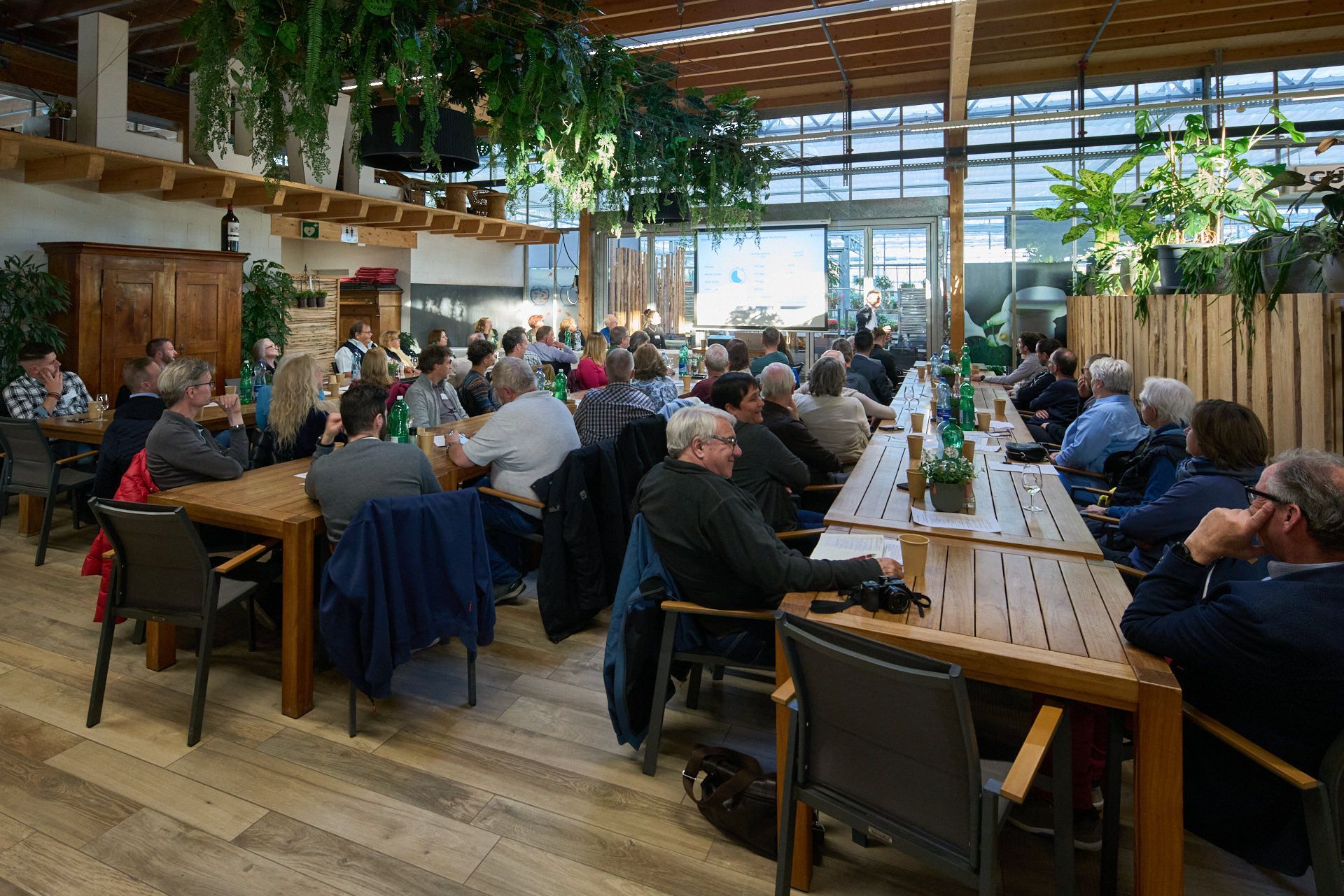 Eine große Gruppe von Menschen sitzt an langen Tischen in einem Restaurant.
