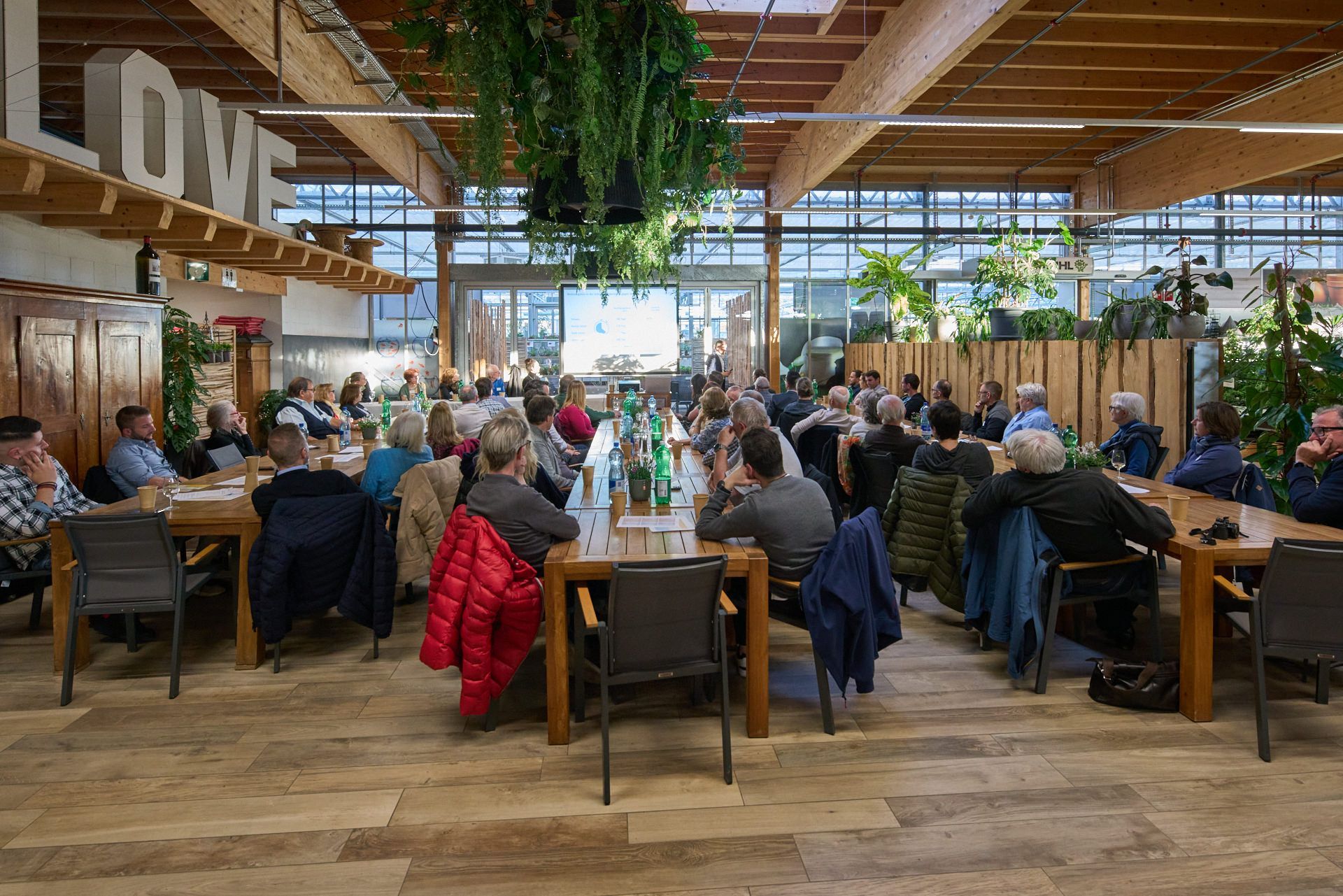 Eine große Gruppe von Menschen sitzt an langen Tischen in einem Restaurant.