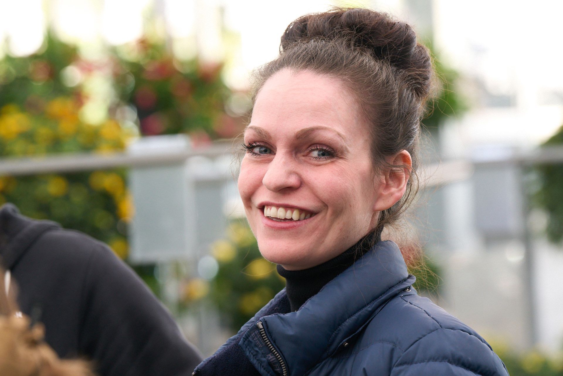 Eine Frau in einer blauen Jacke lächelt in die Kamera.