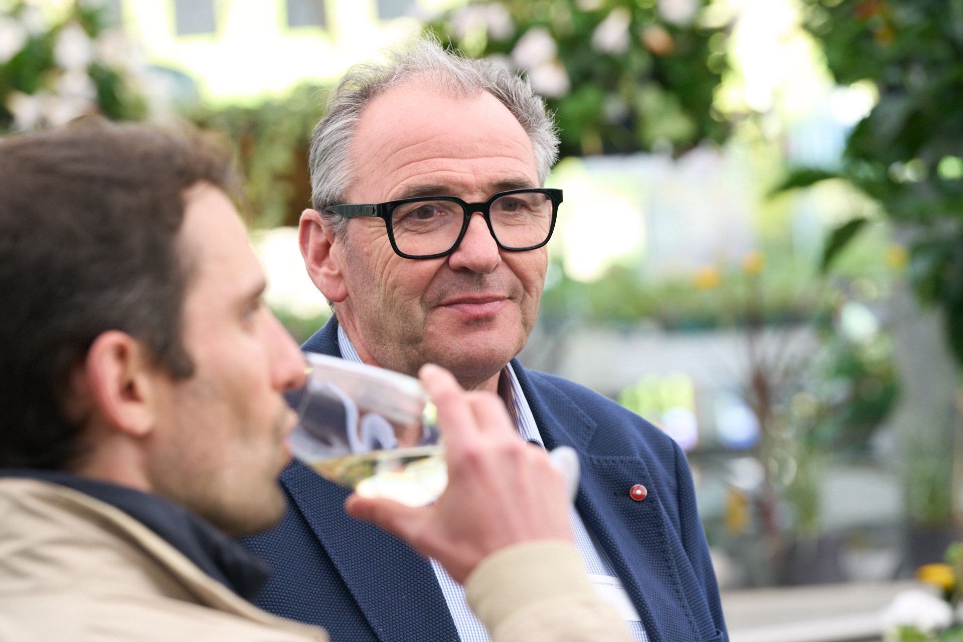 Zwei Männer sitzen nebeneinander und trinken Wein.