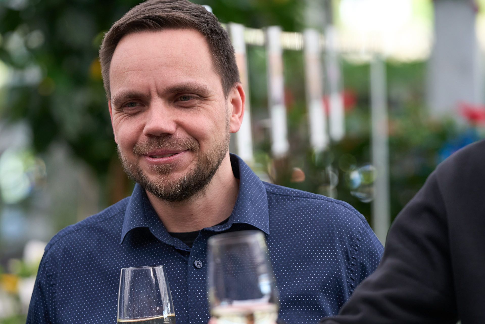 Ein Mann mit Bart hält ein Glas Wein.