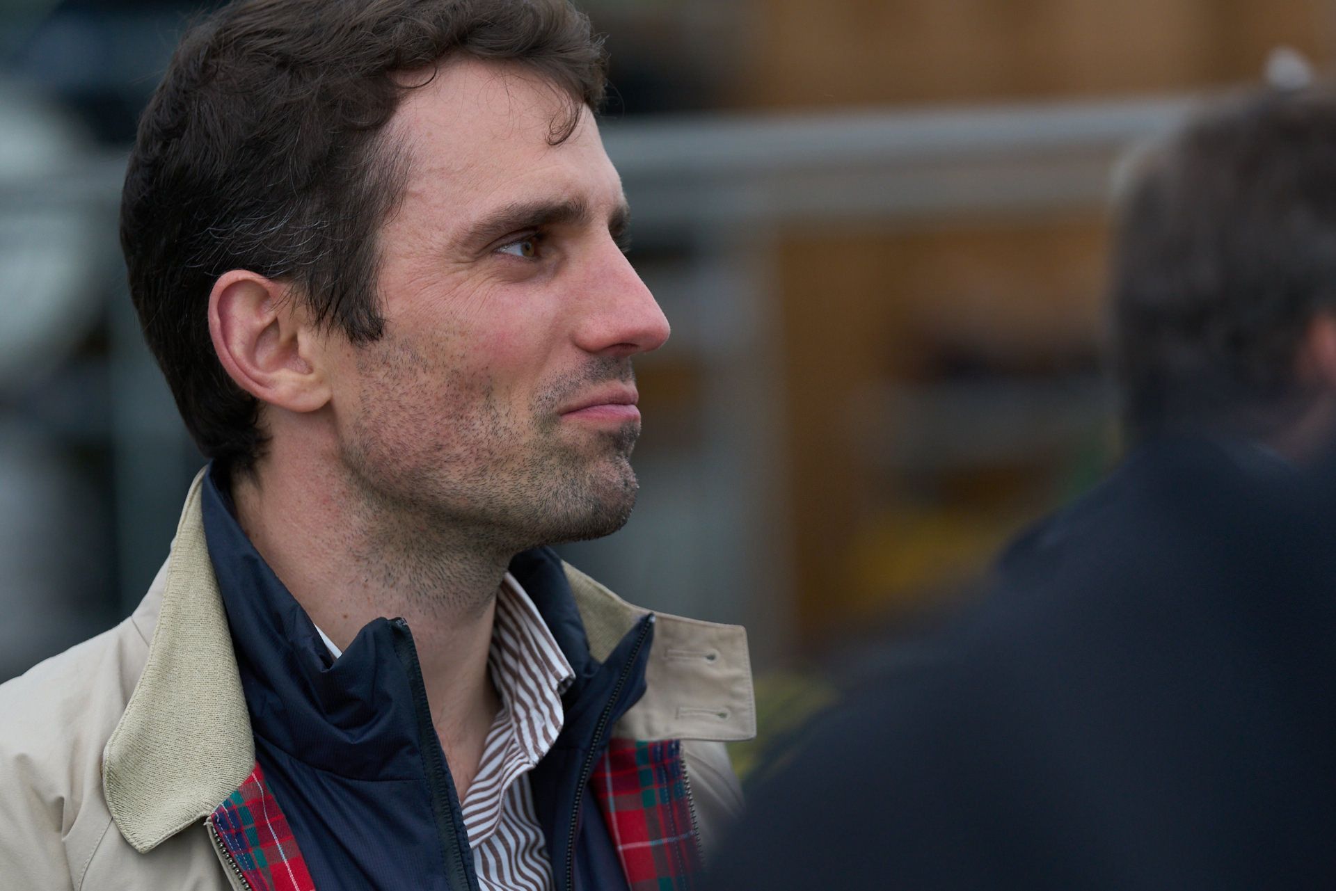 Ein Mann mit Bart trägt ein kariertes Hemd und eine Jacke.