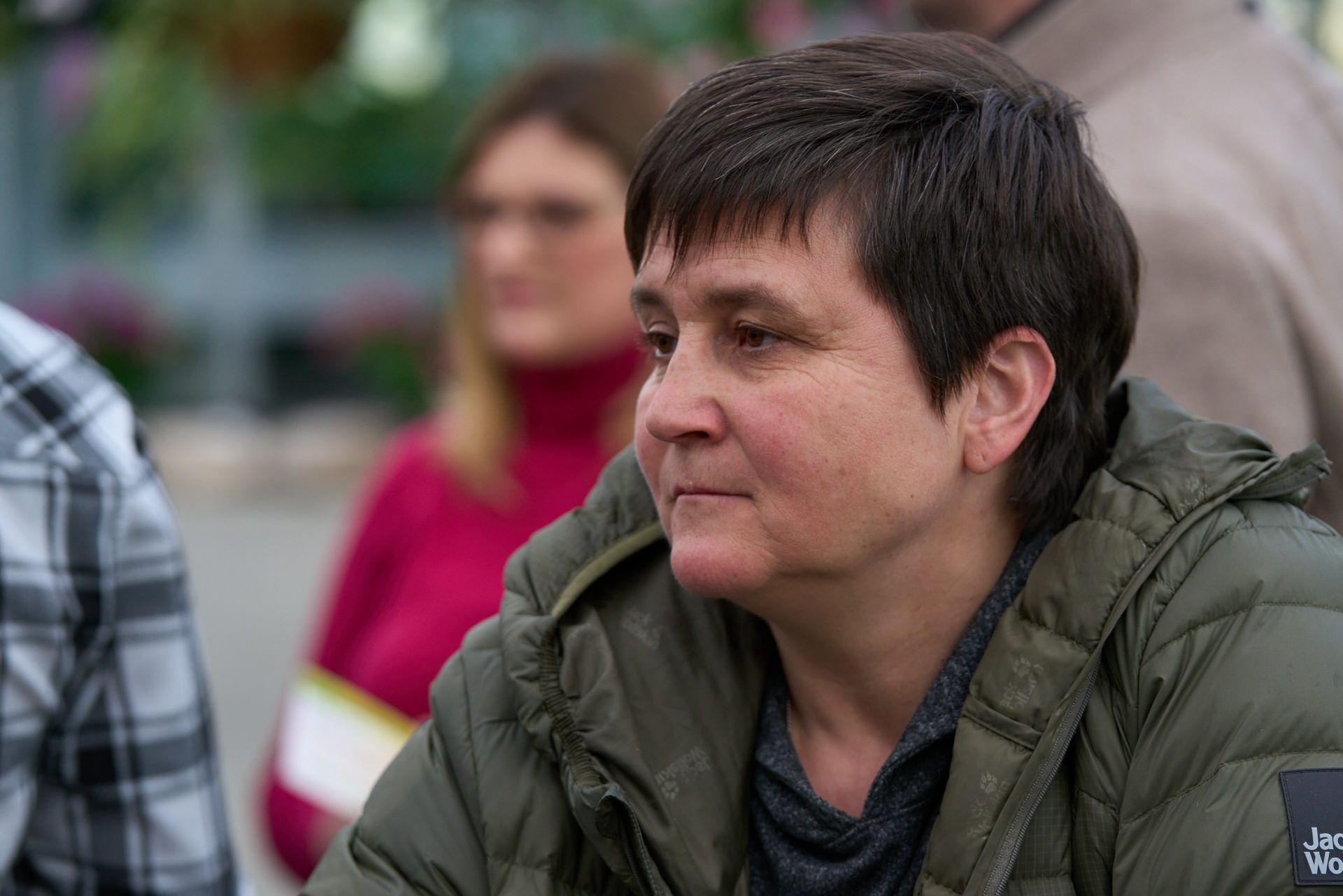 Eine Frau in einer grünen Jacke sitzt vor einer Gruppe von Menschen.