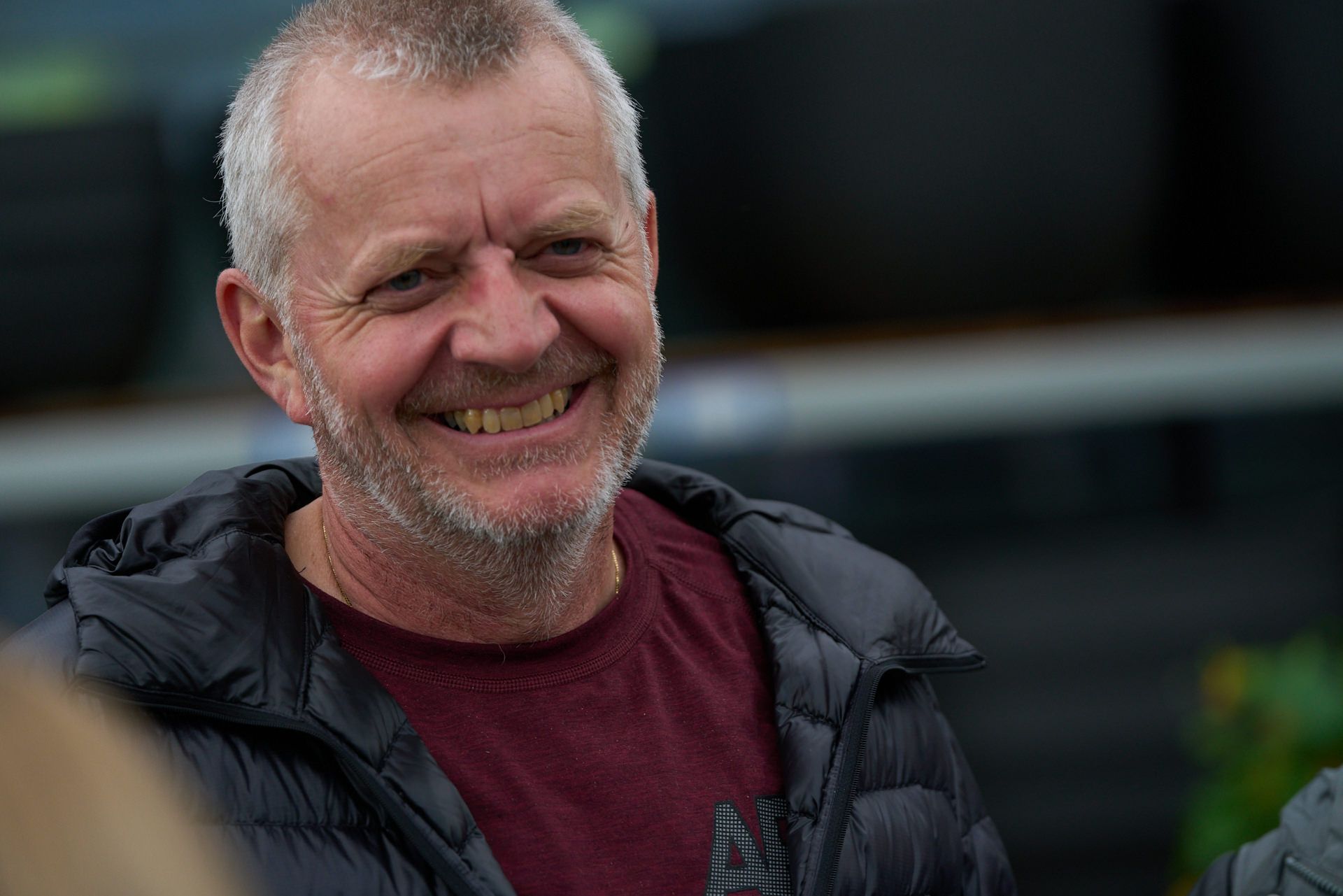 Ein Mann mit Bart lächelt und trägt eine schwarze Jacke.