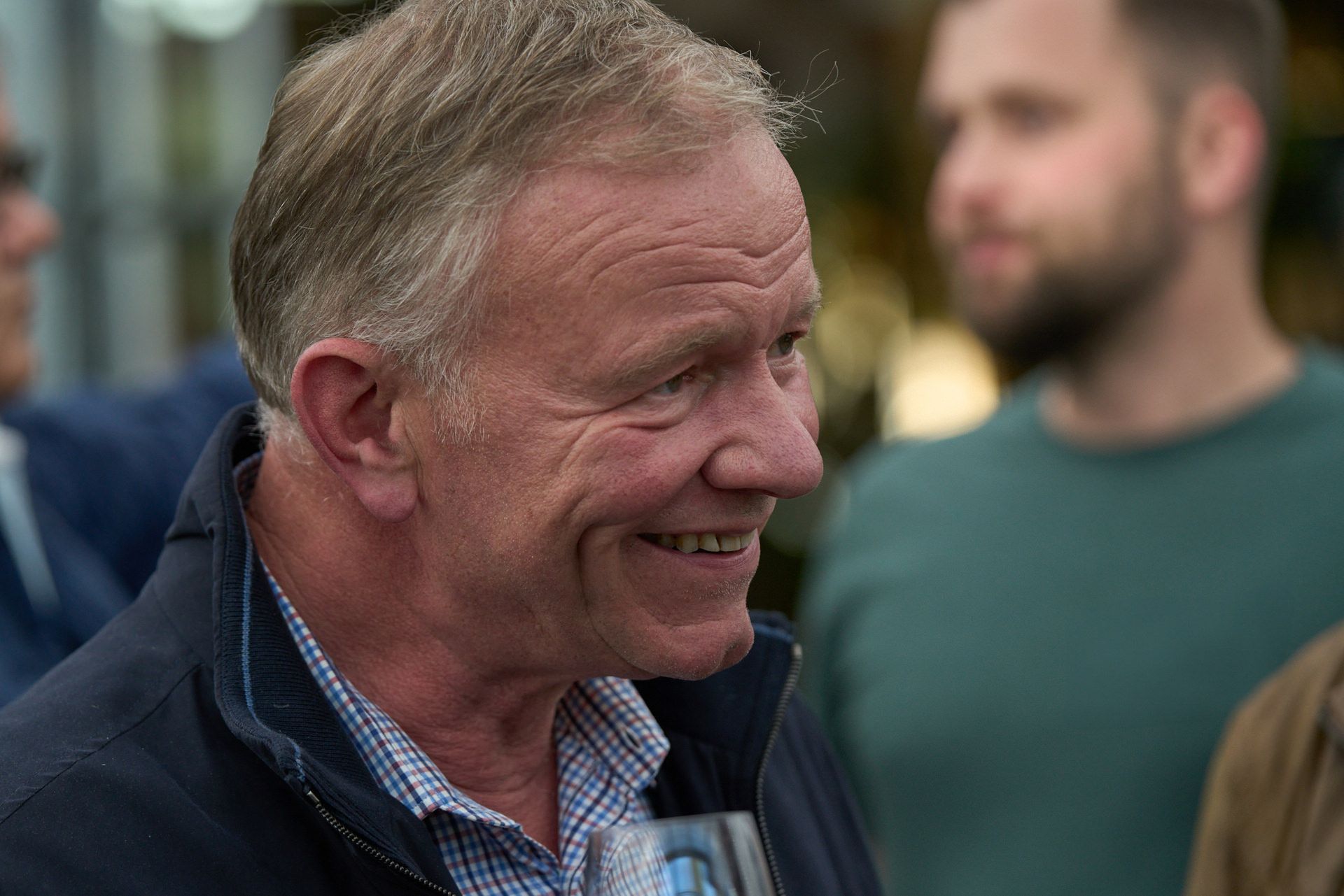 Ein Mann lächelt und hält ein Glas Bier.