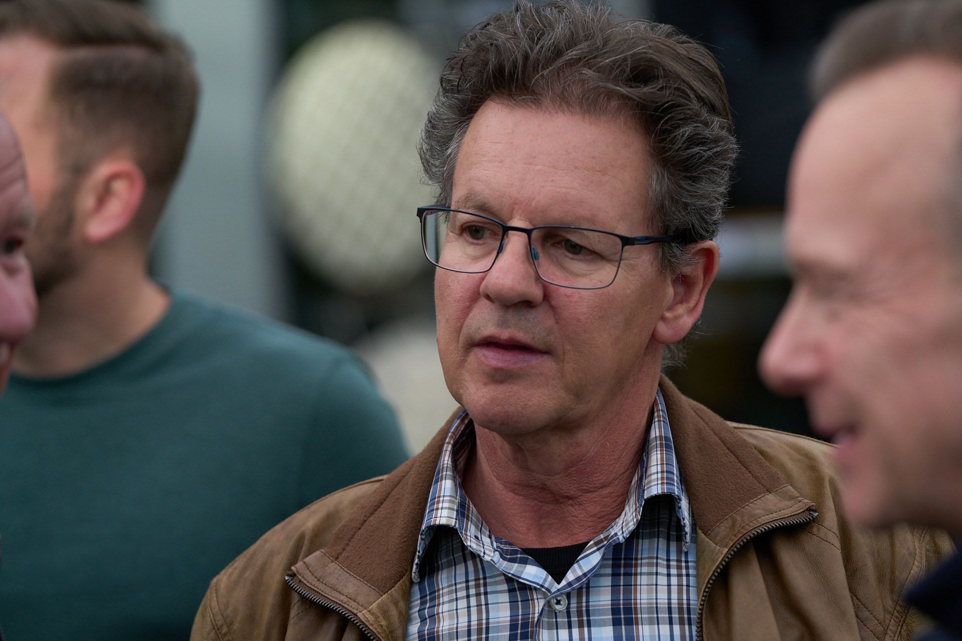 Ein Mann mit Brille und kariertem Hemd steht in einer Menschenmenge.