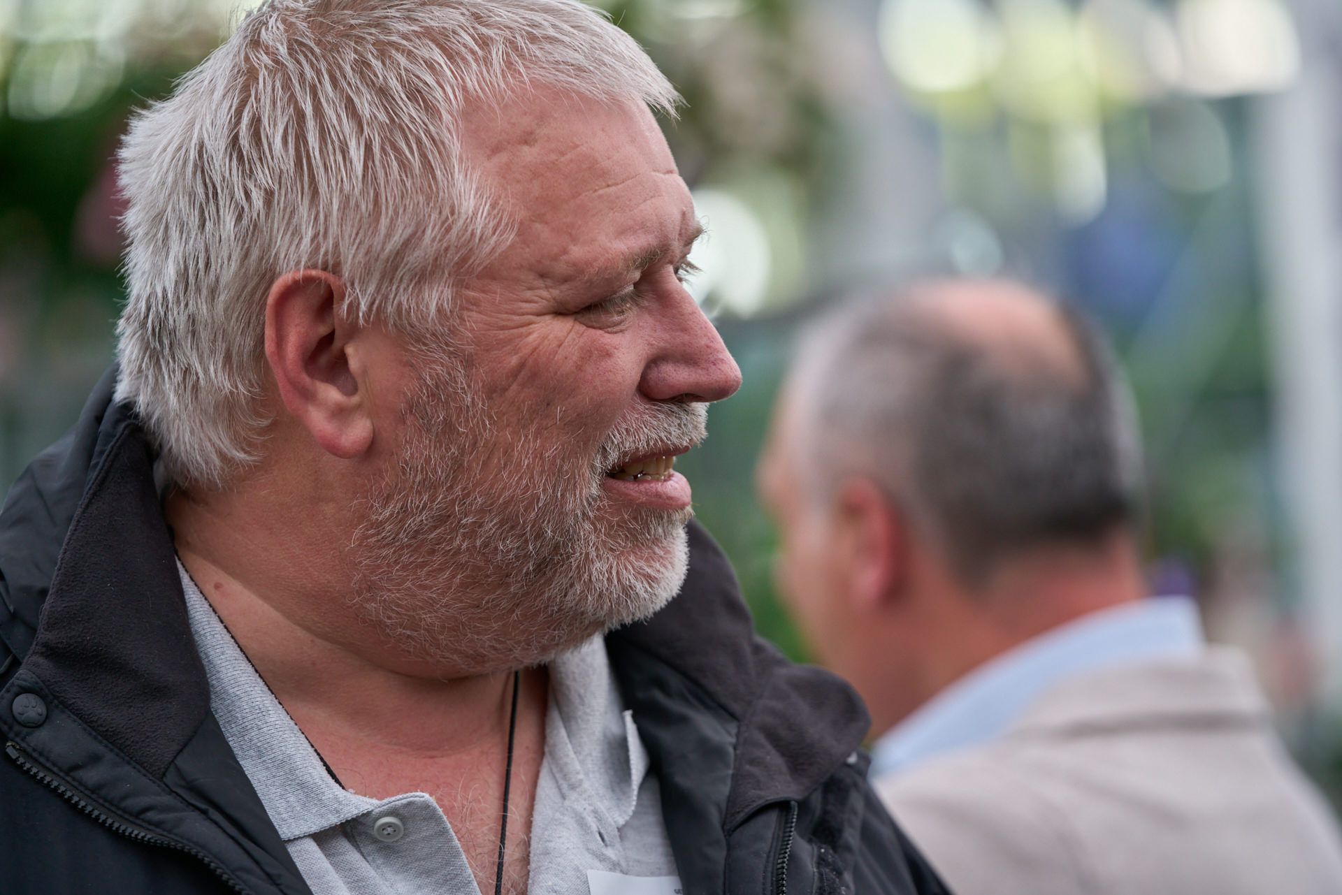 Ein Mann mit grauem Haar und Bart spricht mit einem anderen Mann.