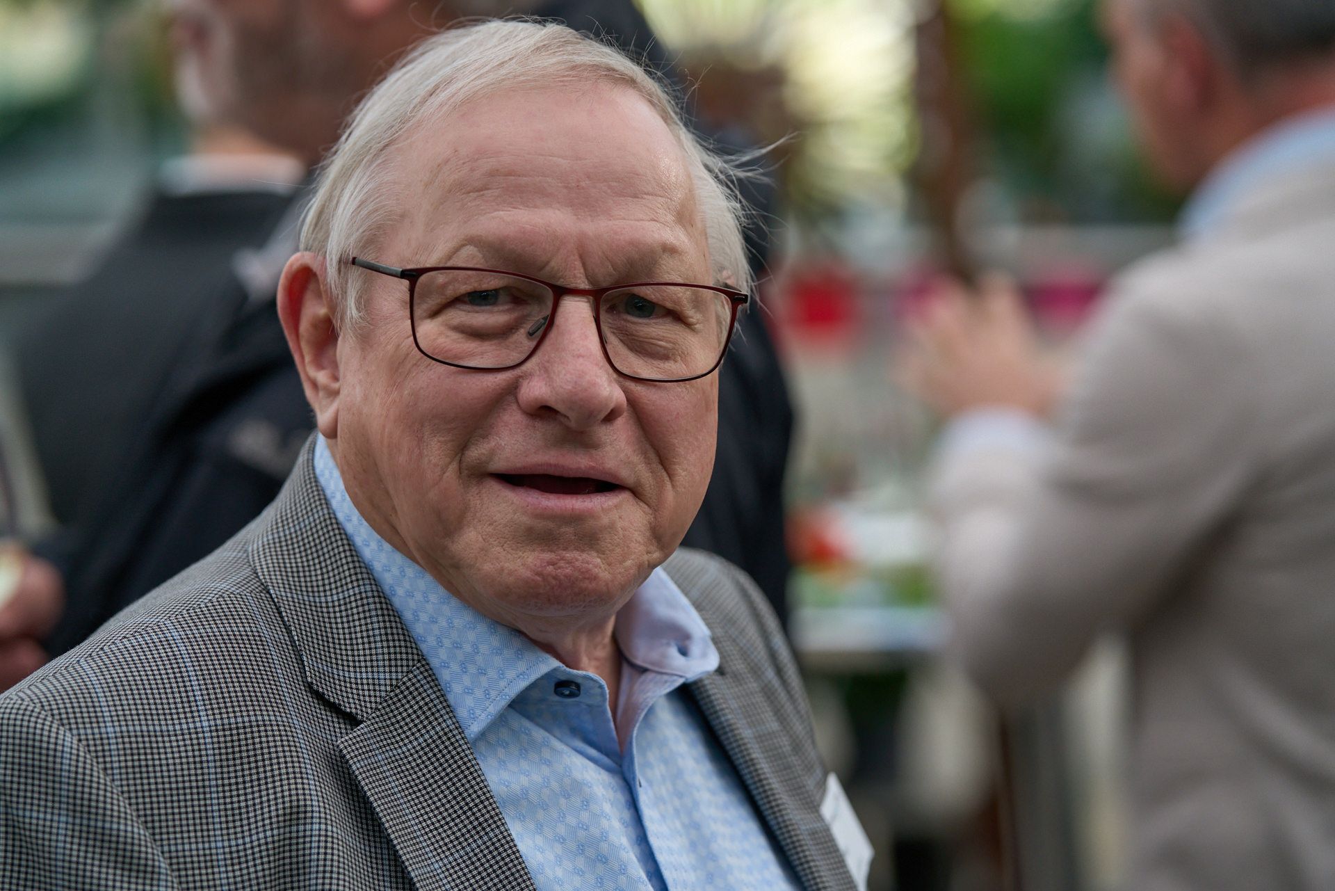 Eine Nahaufnahme eines Mannes mit Brille und Anzug.