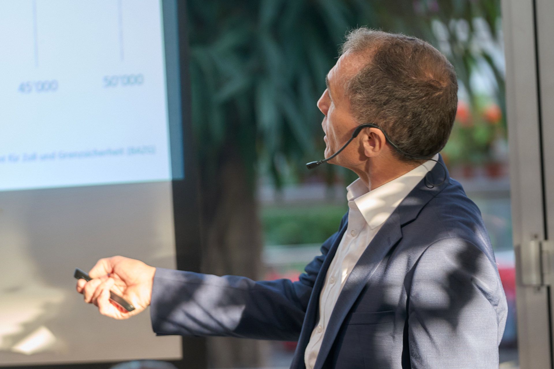 Ein Mann im Anzug und mit Headset hält eine Präsentation.