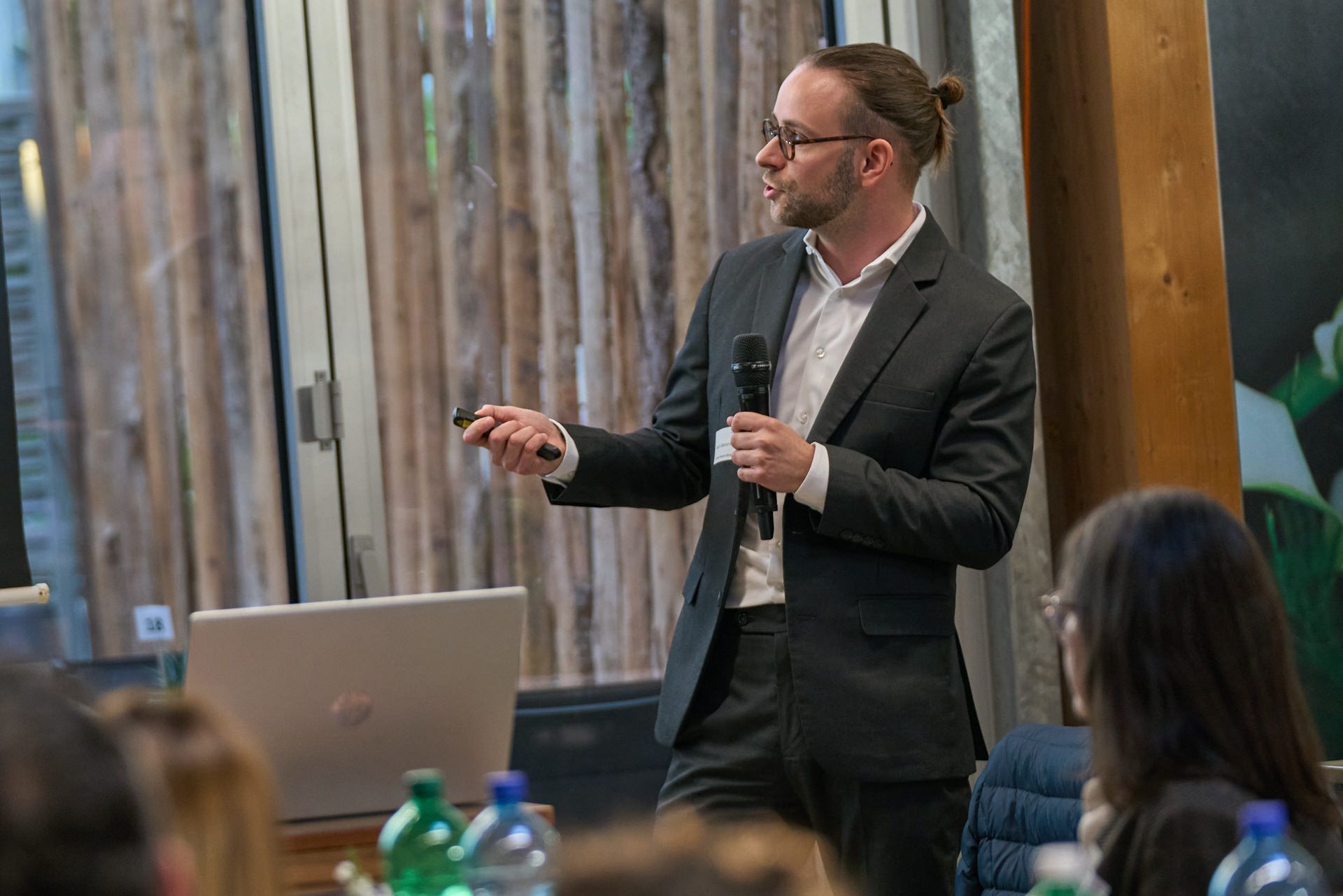 Ein Mann im Anzug hält vor einer Gruppe von Leuten eine Präsentation.