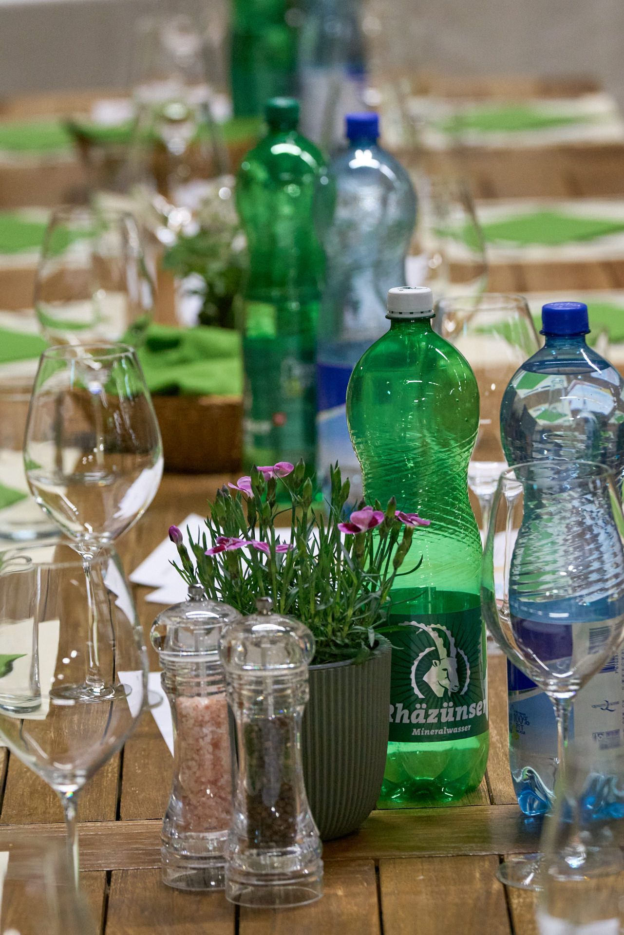 Ein Holztisch mit Wasserflaschen und Weingläsern.