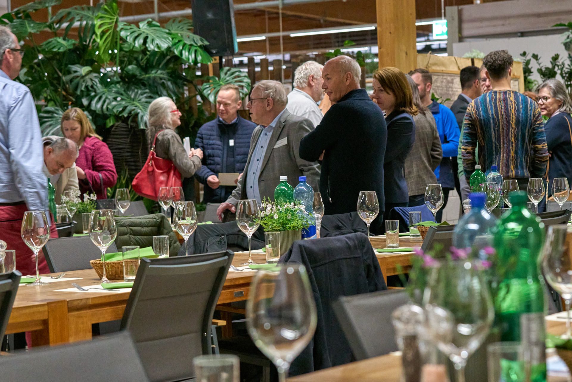 Eine Gruppe von Leuten steht mit Weingläsern um einen Tisch herum.