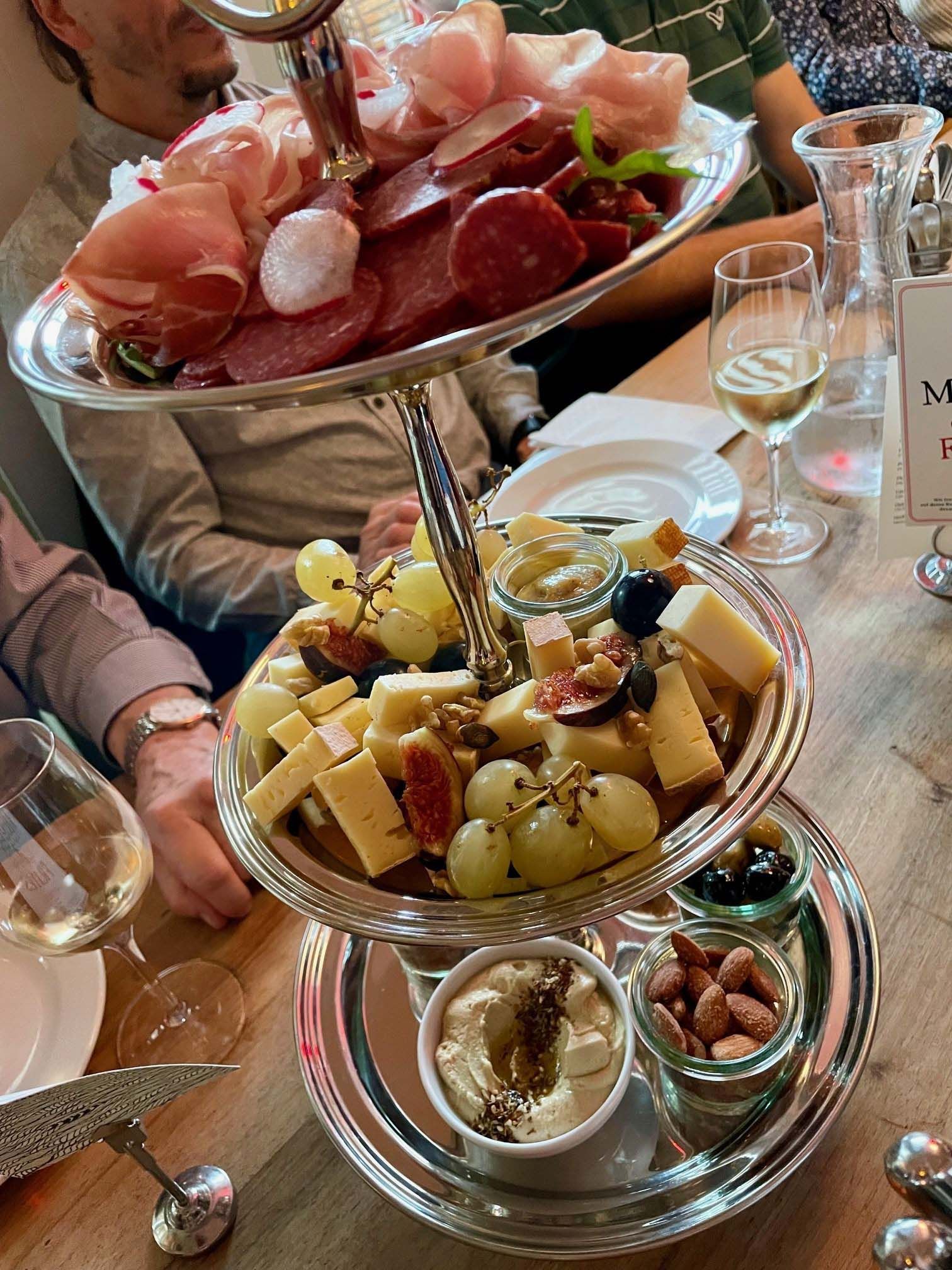 Ein dreistöckiges Tablett voller Essen und Weingläser auf einem Tisch.