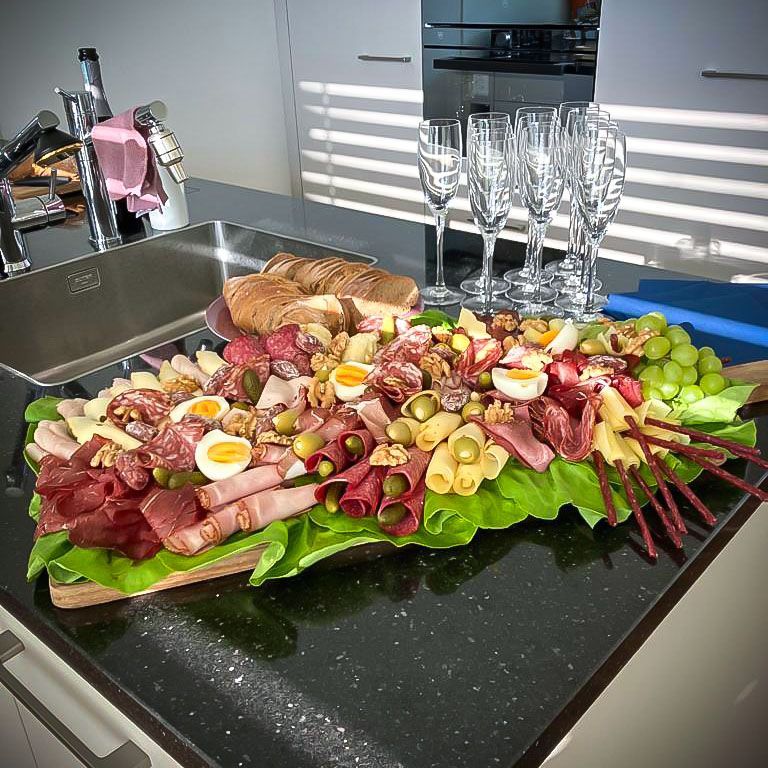 Ein großes Tablett mit Essen und Weingläsern auf einer Theke.