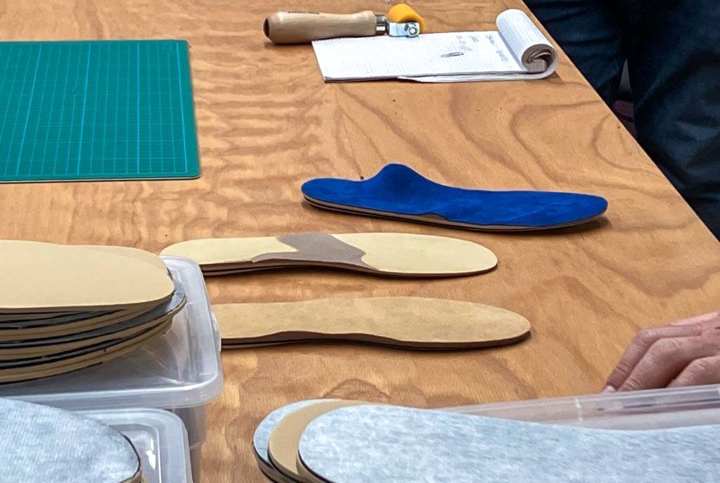 Ein Holztisch mit einem Haufen Einlegesohlen darauf