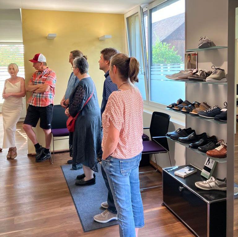 Eine Gruppe von Menschen steht in einem Raum und schaut sich Schuhe an