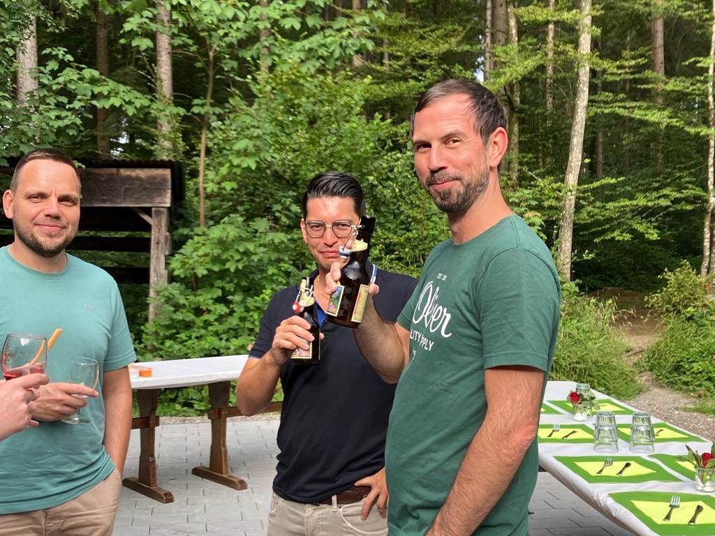 Drei Männer stehen nebeneinander und halten Bierflaschen.