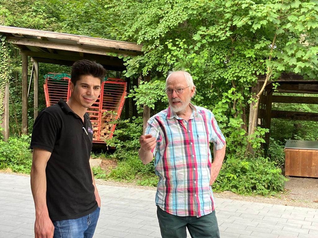 Zwei Männer stehen nebeneinander auf einem Bürgersteig.