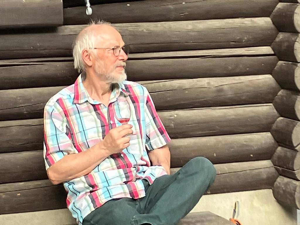 Ein Mann sitzt auf dem Boden und hält ein Glas Wein.