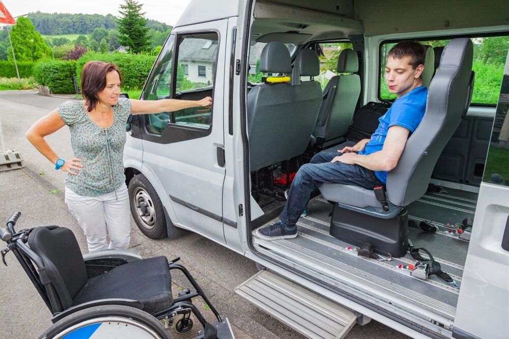 A Woman is Standing Next to a Man in a Wheelchair in a Van — Empowering You Disability Services In Maryborough, QLD
