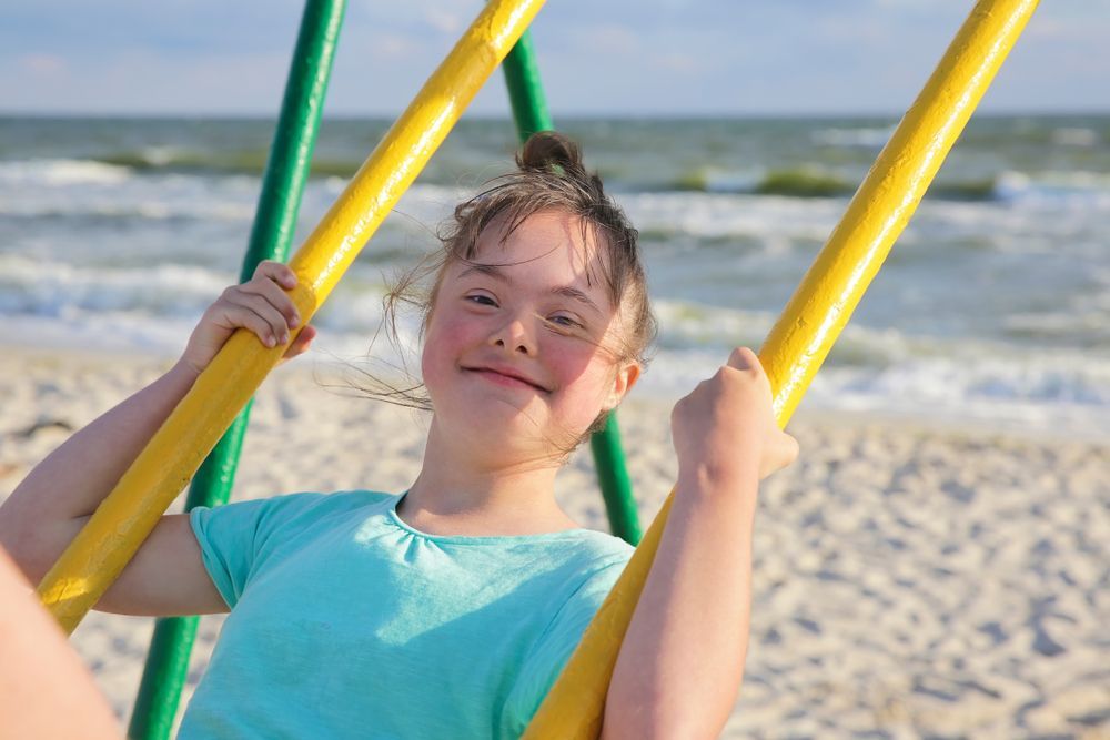 A Girl in a Swing at the Beach  — Empowering You Disability Services In Maryborough, QLD